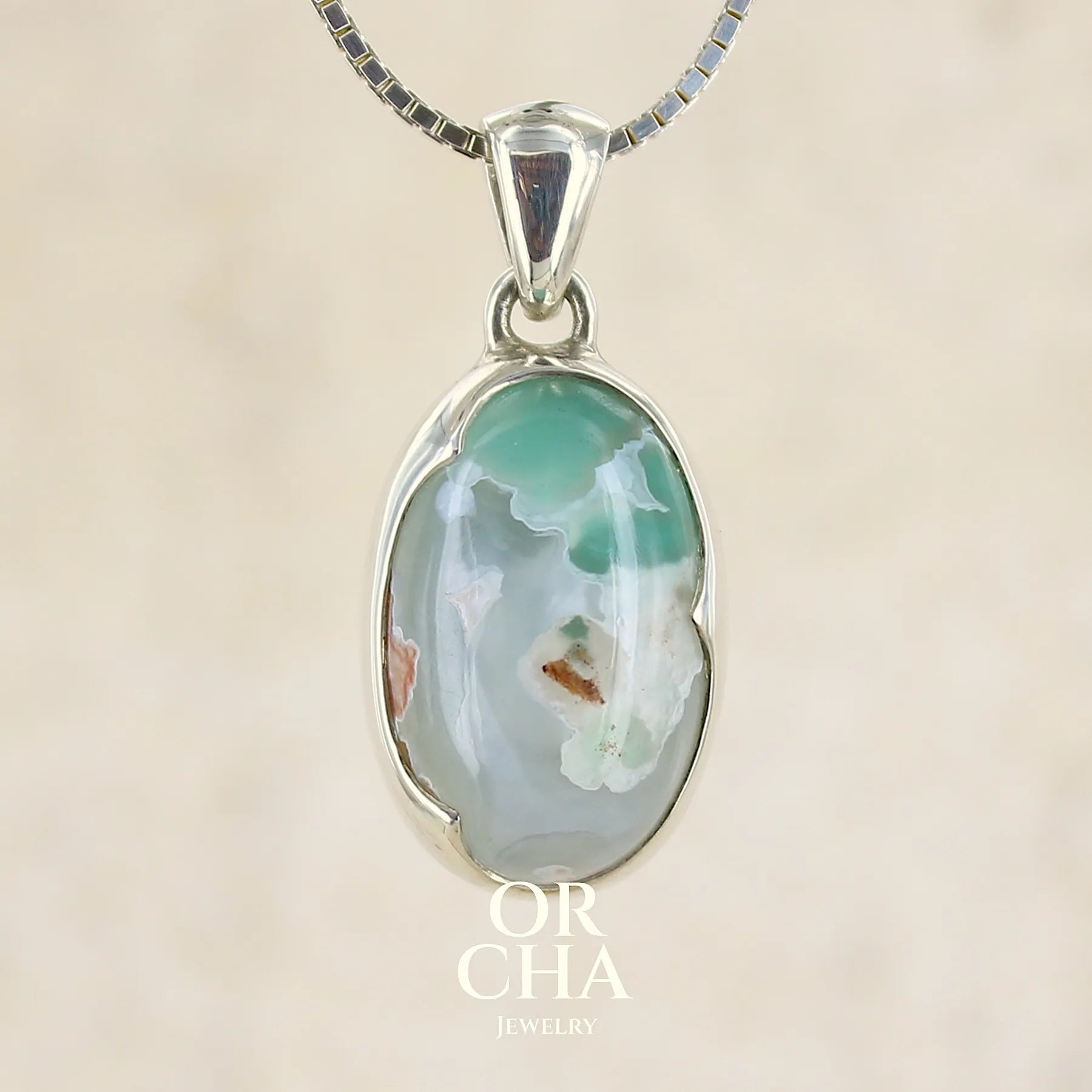 Pendentif ovale en argent massif, serti d'un cabochon de calcédoine de couleur blanche verte. Pierre de qualité translucide comportant des inclusions paysages blanches. Bijoux unique par Orcha Jewelry