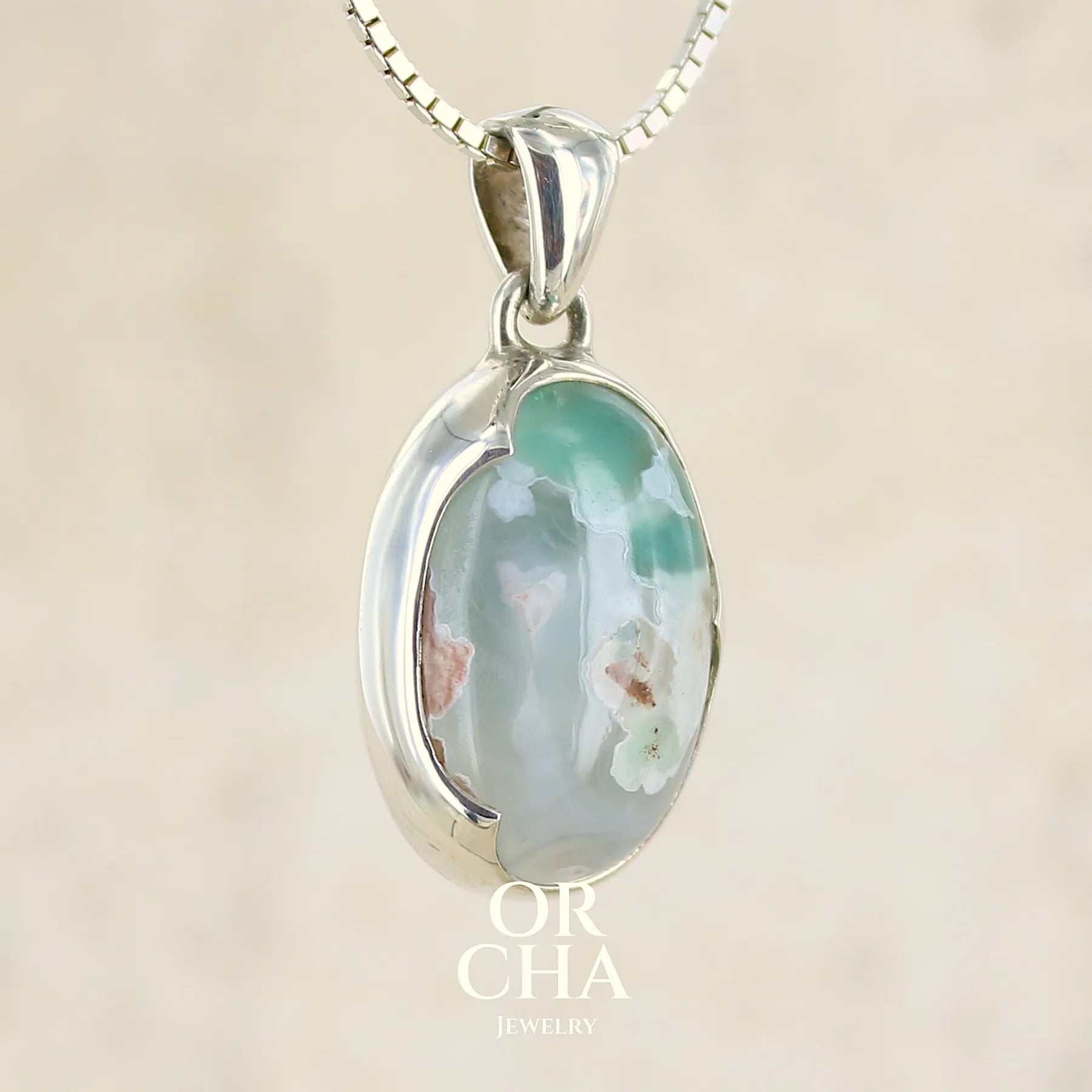 Pendentif ovale en argent massif, serti d'un cabochon de calcédoine de couleur blanche verte. Pierre de qualité translucide comportant des inclusions paysages blanches. Bijoux unique par Orcha Jewelry