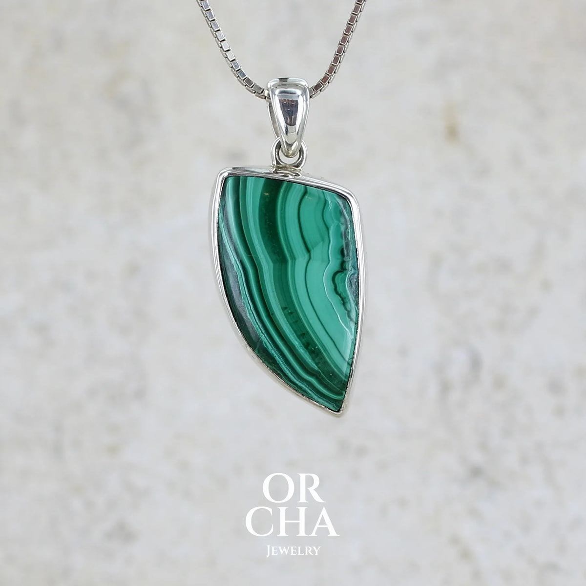 Pendentif pour femme et homme en argent massif serti d'un cabochon de Malachite de couleur verte clair et vert foncé contrasté. Cabochon en forme de dent de qualité opaque. Bijoux unique réalise par Orchajewelry