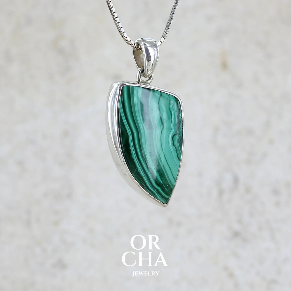 Pendentif pour femme et homme en argent massif serti d'un cabochon de Malachite de couleur verte clair et vert foncé contrasté. Cabochon en forme de dent de qualité opaque. Bijoux unique réalise par Orchajewelry