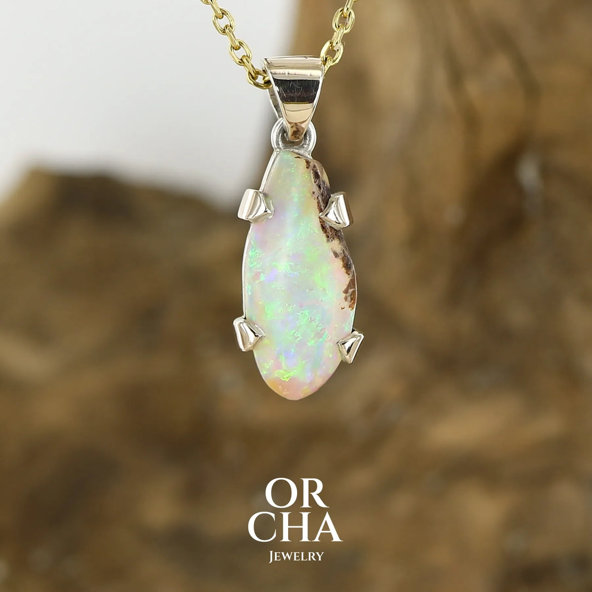 Pendentif pour femme en or 9k et argent massif 925 serti d'une opale cristal aux feux étoilés multicolores à dominantes vert et jaune. Cabochon de 3,3 carats de forme libre et de qualité translucide avec présence de roche mère. Bijou unique réalisé par Orchajewelry