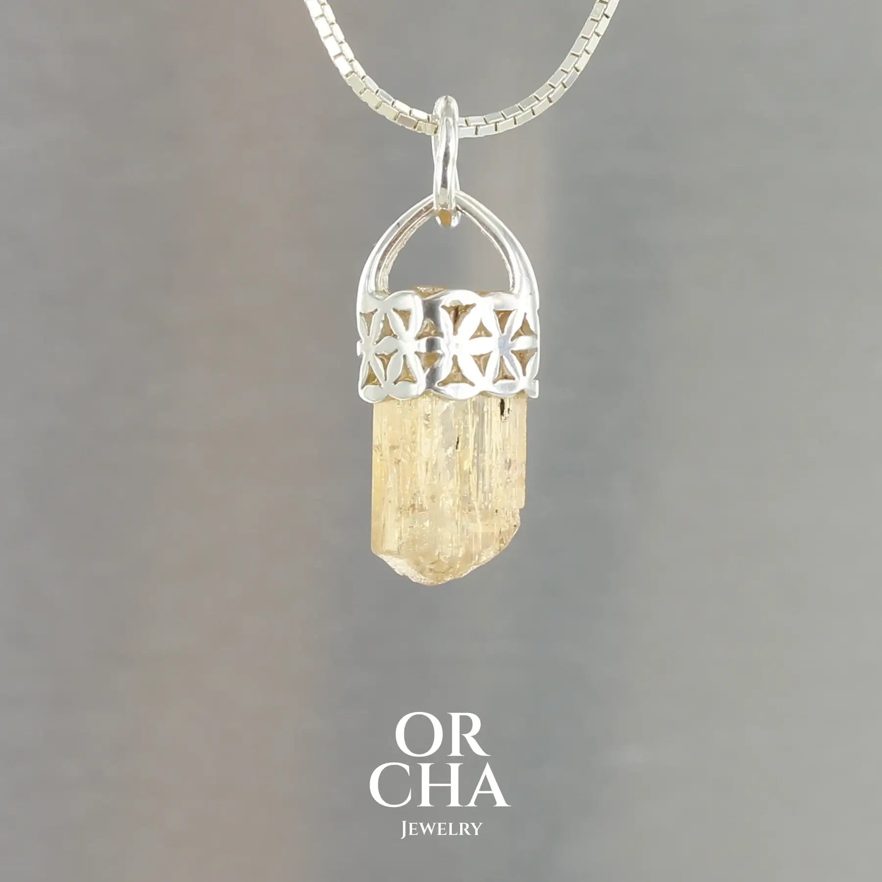 Pendentif fleur de vie pour femme en argent massif serti d'un cristal de topaze impériale de couleur jaune doré miel. Pierre brute transparente présentant des inclusions. Bijoux unique, éthique et durable présenté dans un coffret de notre marque, prêt à offrir. Livraison offerte, certificat d'authenticité, service client.