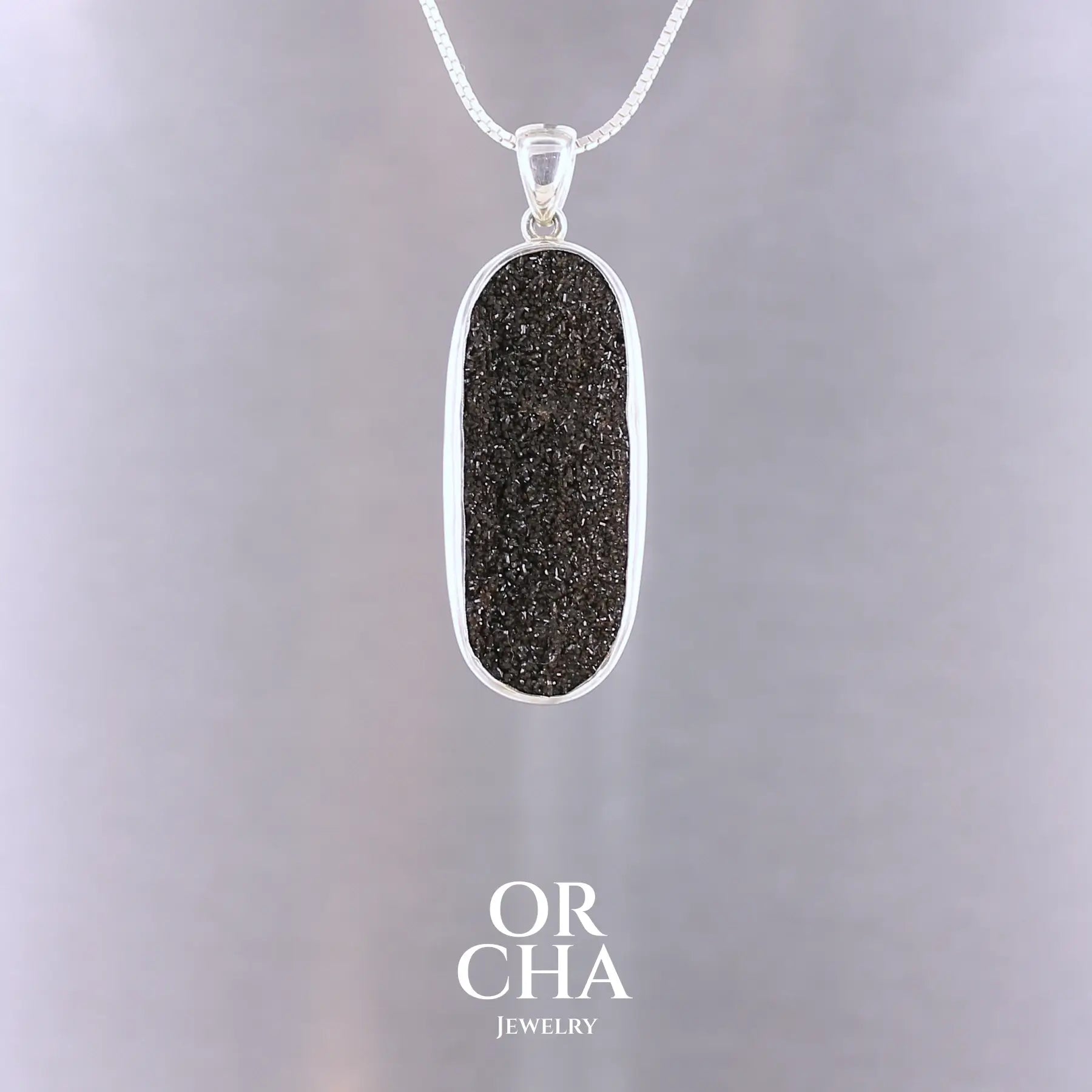 Pendentif en argent massif au design minimaliste, orné d’un cabochon allongé de bois fossilisé brut. La surface naturelle de la pierre, irrégulière et scintillante, capte subtilement la lumière. Bijoux unique, éthique et durable présenté dans un coffret de notre marque, prêt à offrir. Livraison offerte, certificat d'authenticité, service client