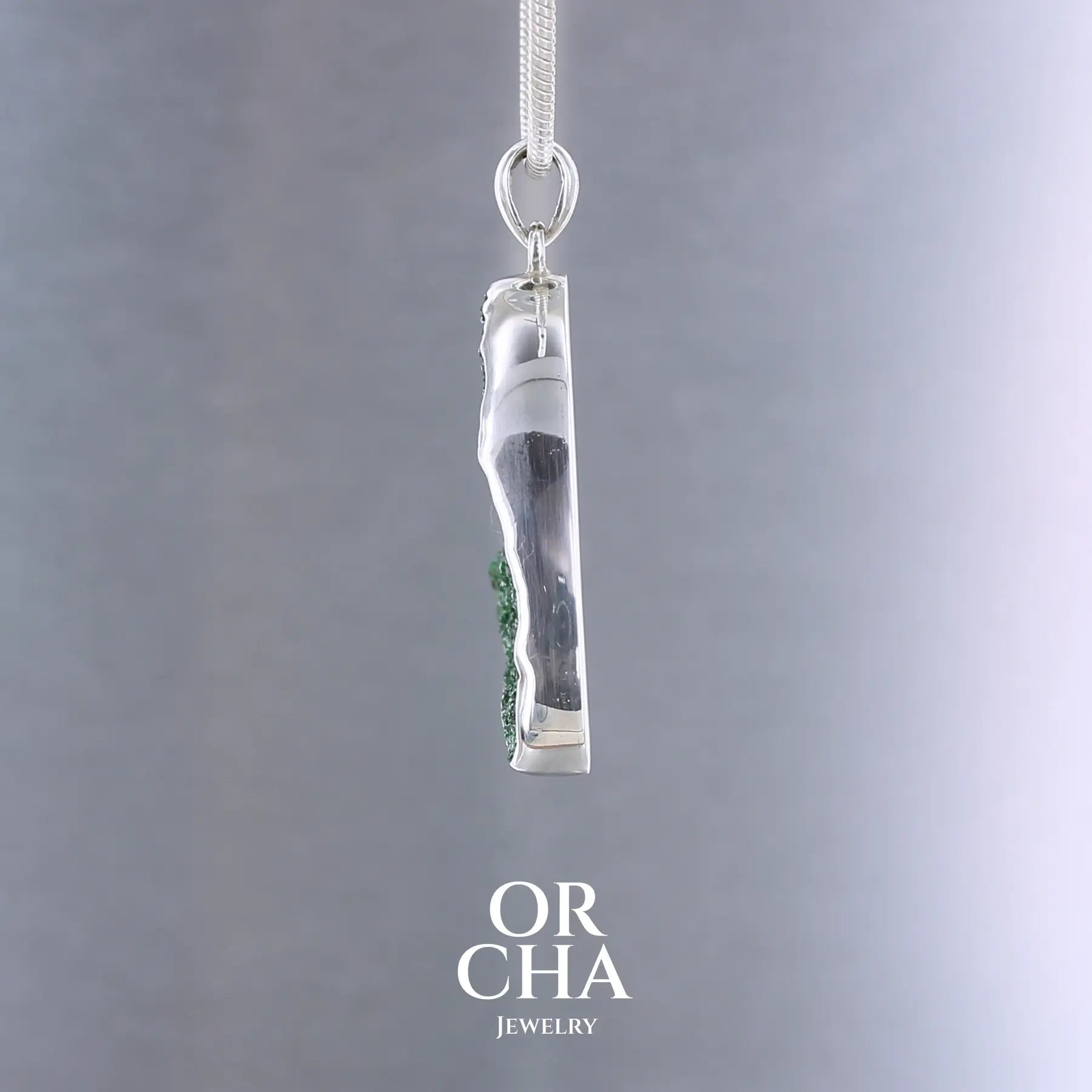 Pendentif en argent massif serti d'un grenat Uvarovite brute. Pierre naturelle recouverte de cristaux scintillants de couleur verte, taillée en forme de goutte. Bijoux unique, éthique et durable présenté dans un coffret de notre marque, prêt à offrir. Livraison offerte, certificat d'authenticité, service client.