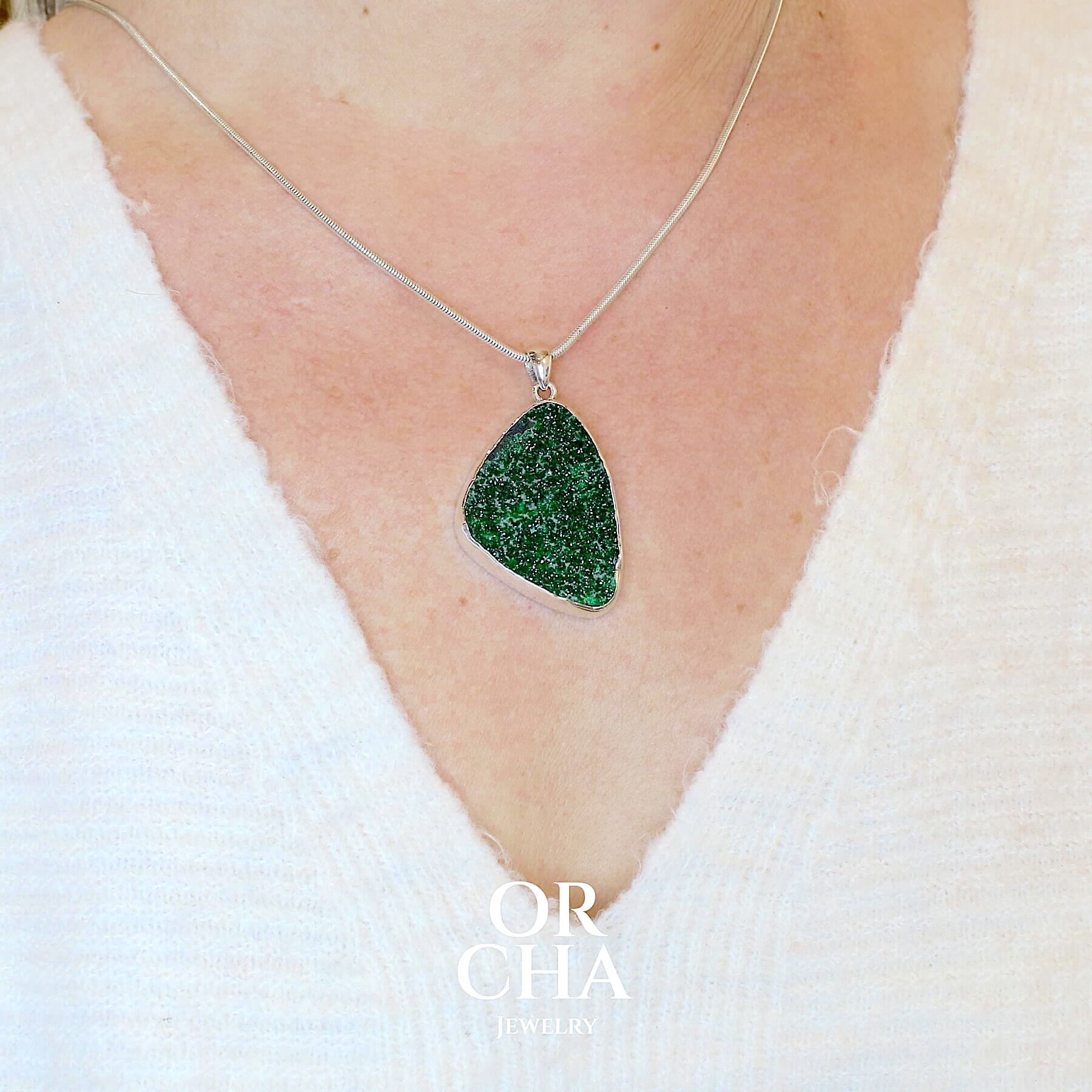 Pendentif en argent massif serti d'un grenat Uvarovite brute. Pierre naturelle recouverte de cristaux scintillants de couleur verte, taillée en forme de goutte. Bijoux unique, éthique et durable présenté dans un coffret de notre marque, prêt à offrir. Livraison offerte, certificat d'authenticité, service client.
