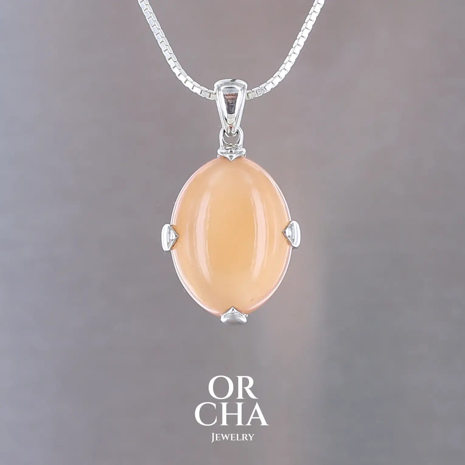 Pendentif pour femme en argent massif serti d'une pierre de lune orange. Pierre cabochon de forme ovale de couleur orange chatoyante à effet satiné. Bijoux unique, éthique et durable présenté dans un coffret de notre marque, prêt à offrir. Livraison offerte, certificat d'authenticité, service client.