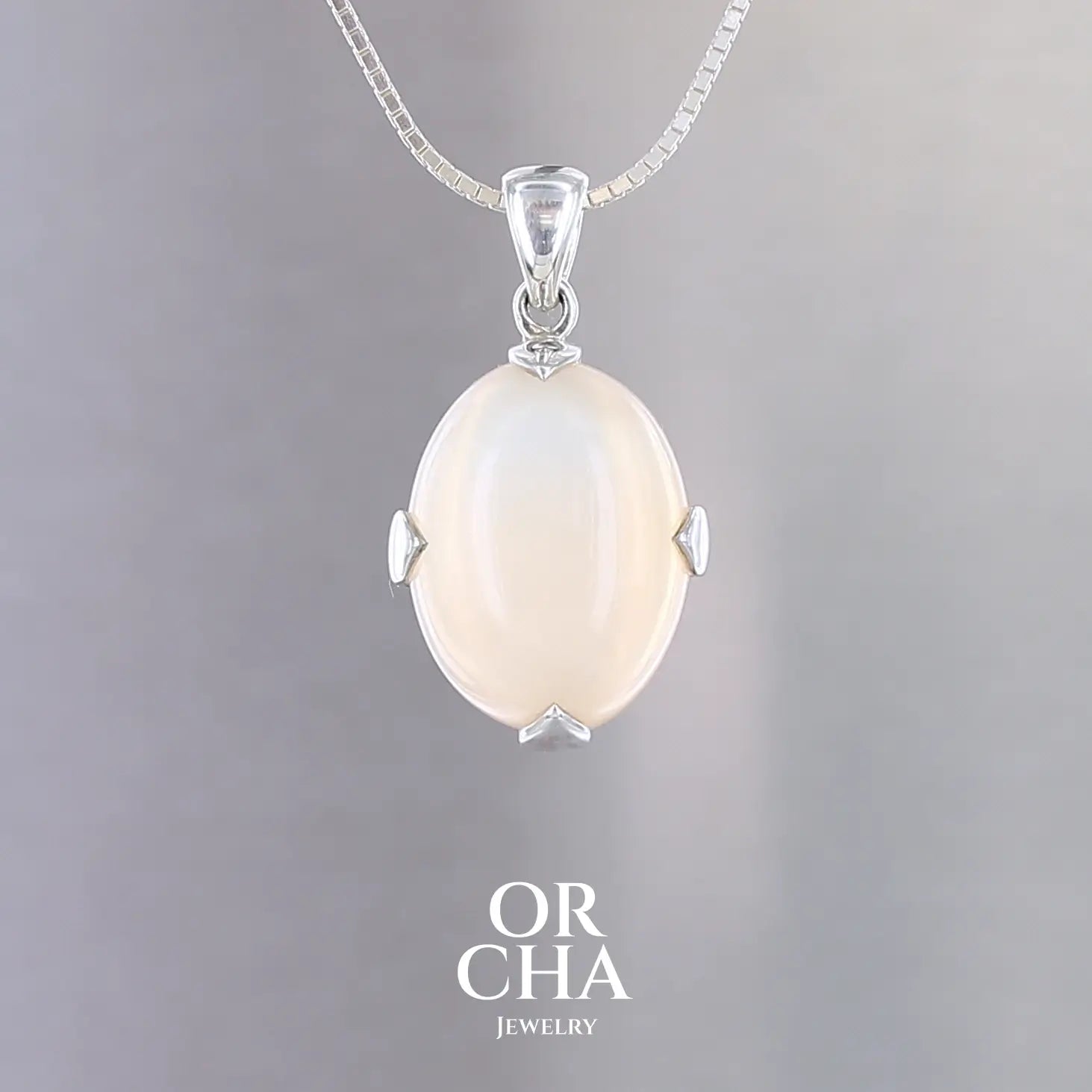 Pendentif pour femme en argent massif serti d'une pierre de lune orange clair, couleur chatoyante à effet satiné. Pierre naturelle taillée en cabochon de forme ovale serti de griffe. Bijoux unique, éthique et durable présenté dans un coffret de notre marque, prêt à offrir. Livraison offerte, certificat d'authenticité, service client