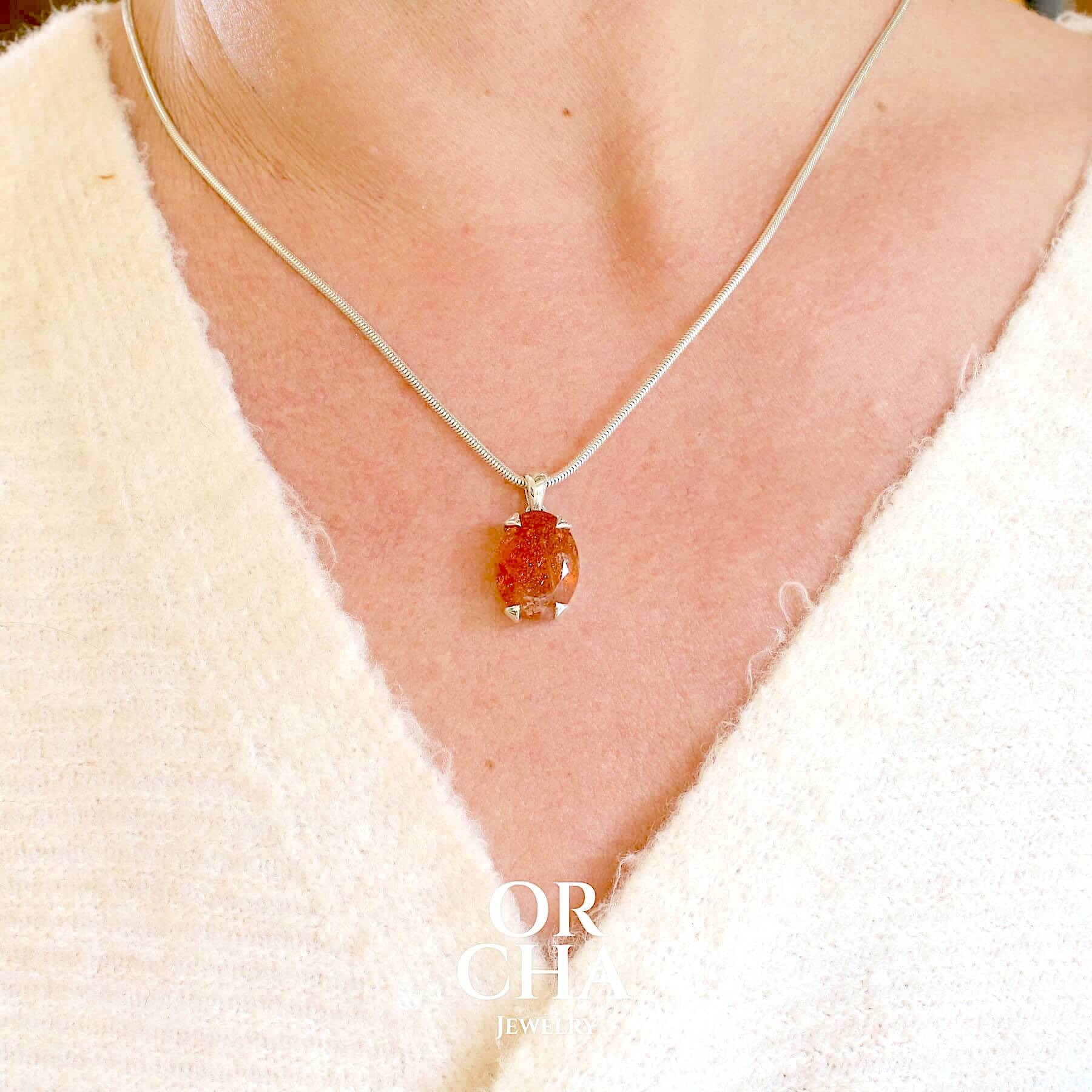 Pendentif en argent massif serti d'une magnifique pierre de soleil. Pierre facettée de forme ovale de qualité transparente. Pierre naturelle de couleur orange à scintillement doré et orangé. Bijoux unique, éthique et durable présenté dans un coffret de notre marque, prêt à offrir. Livraison offerte, certificat d'authenticité, service client.