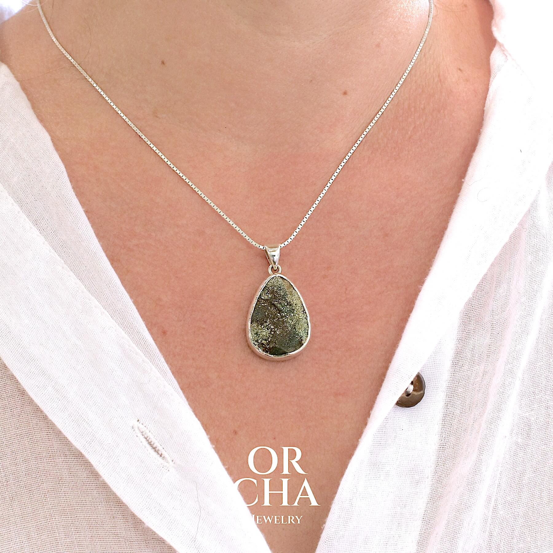Pendentif en forme de goutte pour femme en argent massif serti d'une pyrite brute scintillante. Pierre naturelle de couleur dorés et brune de qualité Druze scintillante. Bijoux unique, éthique et durable présenté dans un coffret de notre marque, prêt à offrir. Livraison offerte, certificat d'authenticité, service client.