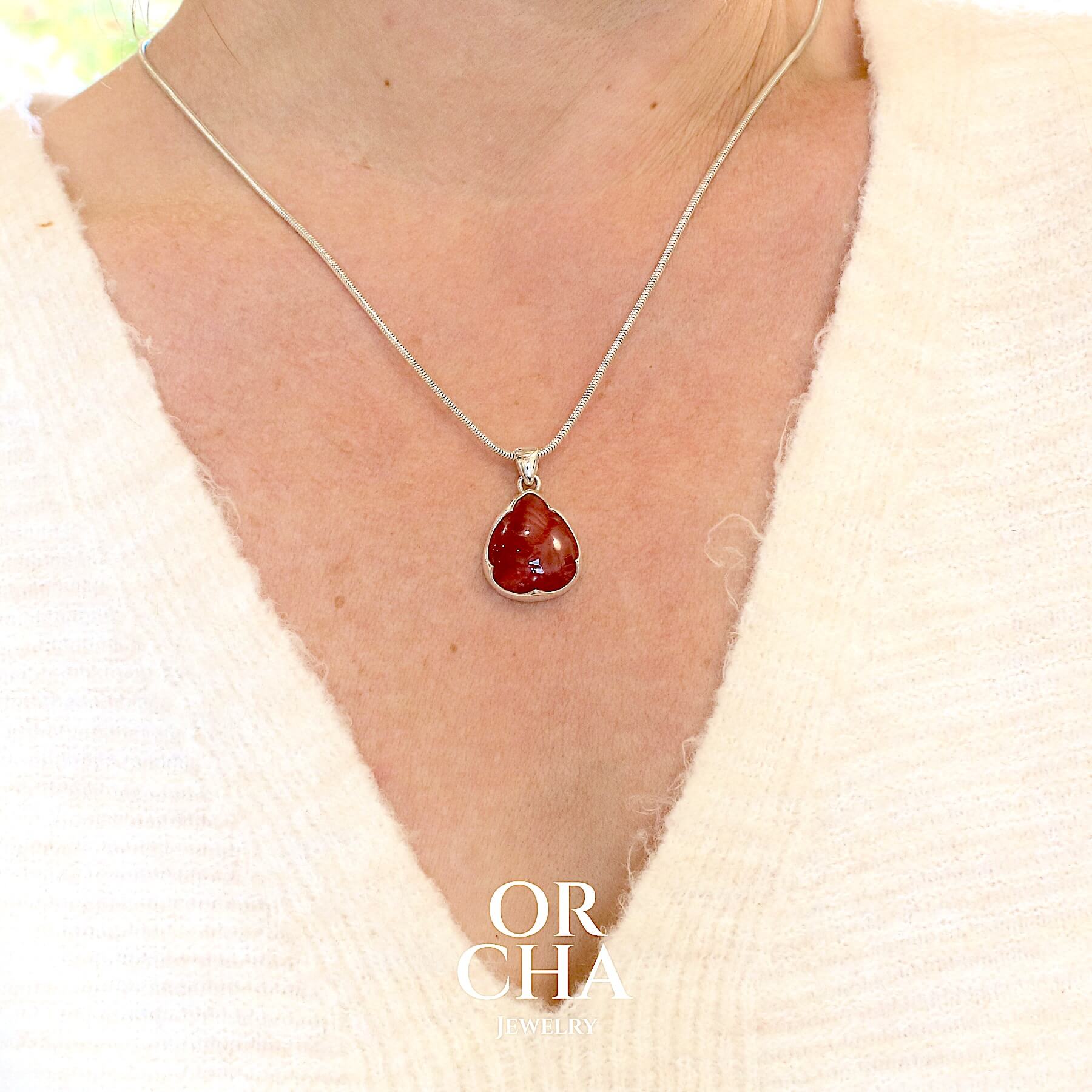 Pendentif pour femme en argent massif serti d'une Rhodonite de belle qualité. Pierre de couleur rouge coquelicot, opaque à inclusions. Pierre naturelle, en forme de goutte, taillée en cabochon. Bijoux unique, éthique et durable présenté dans un coffret de notre marque, prêt à offrir. Livraison offerte, certificat d'authenticité, service client