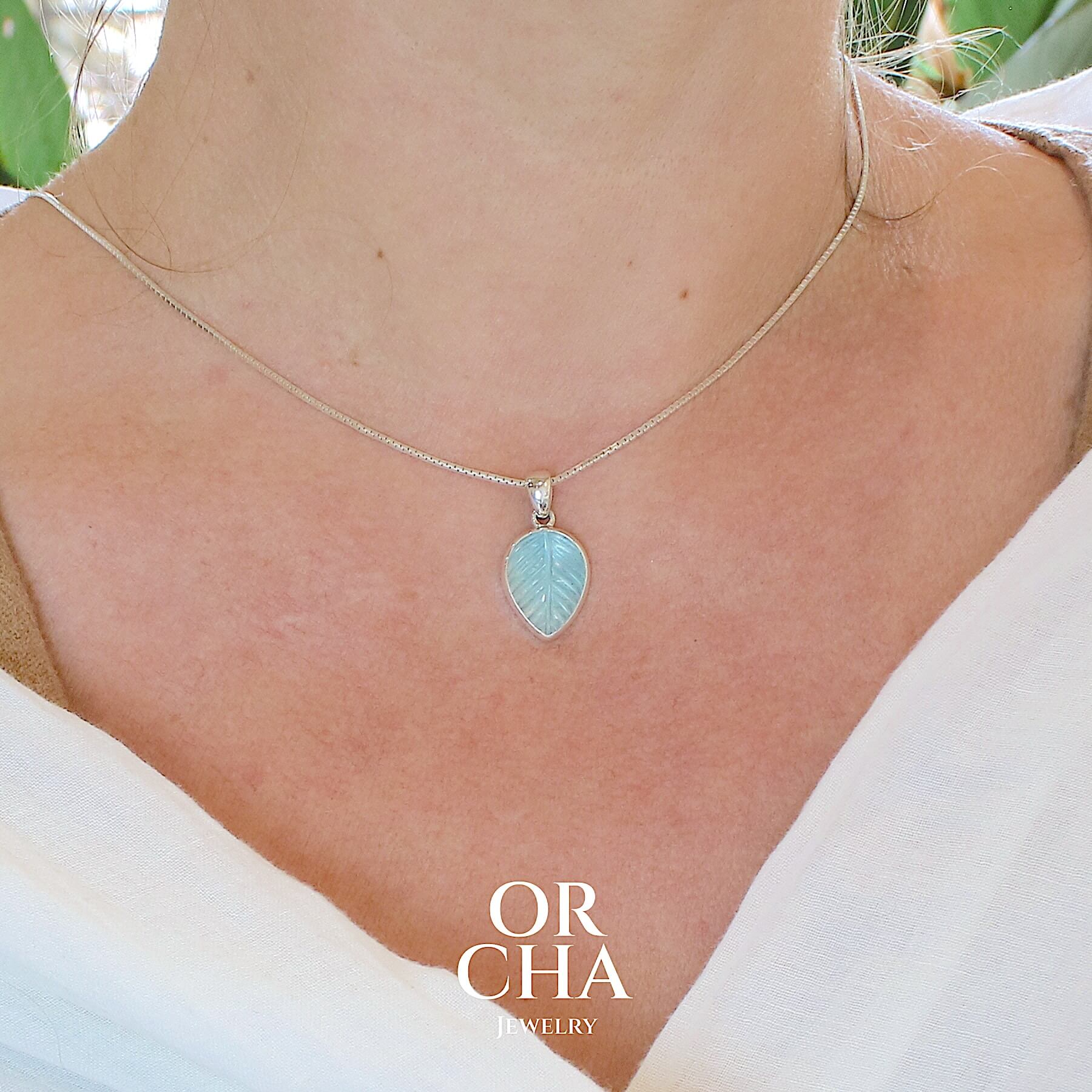 Pendentif pour femme en argent massif serti d'une topaze bleue sculptée en forme de feuille d'arbre. Pierre de couleur bleu ciel lumineux. Bijoux unique, éthique et durable présenté dans un coffret de notre marque, prêt à offrir. Livraison offerte, certificat d'authenticité, service client.