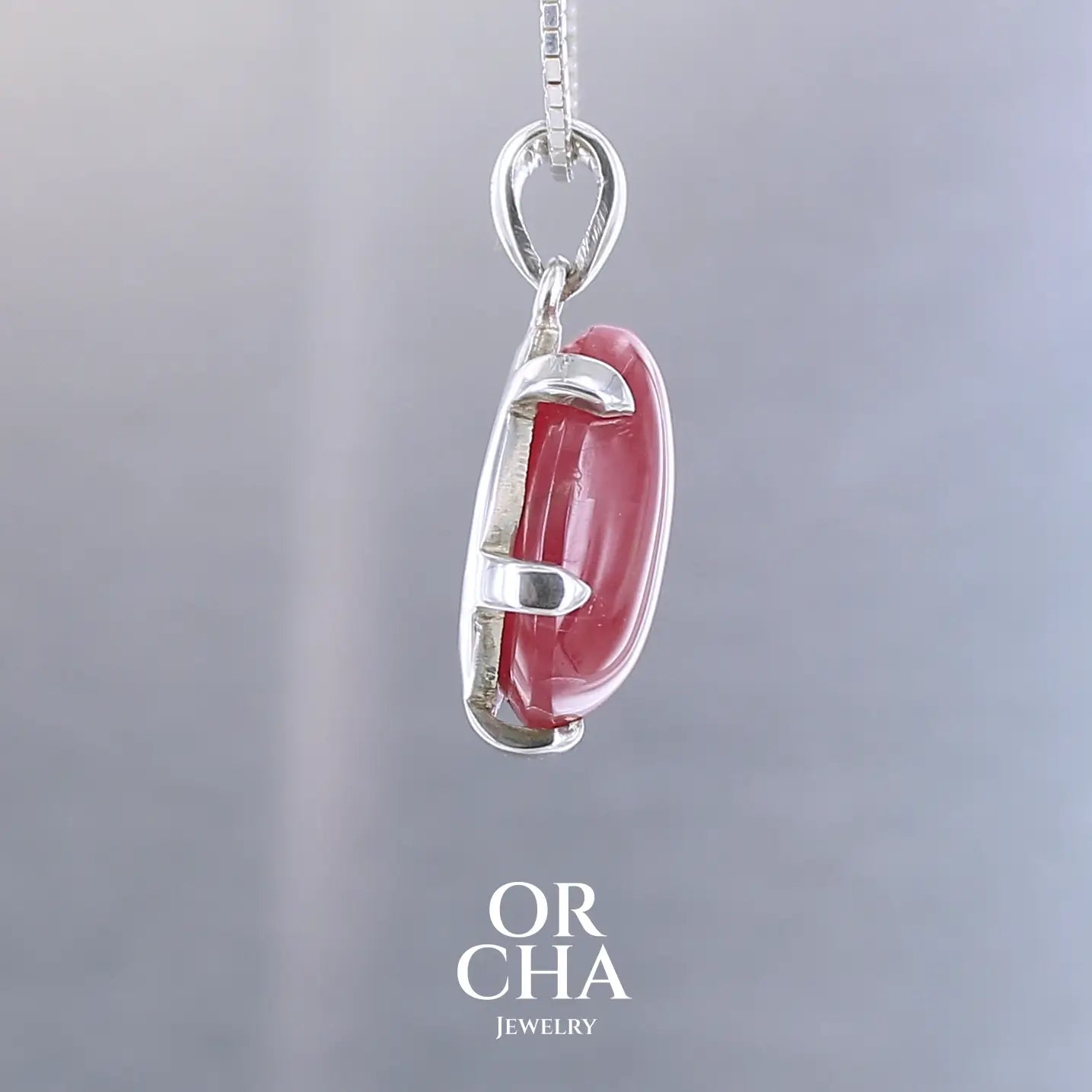 Pendentif pour femme en argent massif serti d'une Rhodonite de belle qualité. Pierre de couleur rouge coquelicot, opaque à inclusions. Pierre naturelle, en forme de goutte, taillée en cabochon. Bijoux unique, éthique et durable présenté dans un coffret de notre marque, prêt à offrir. Livraison offerte, certificat d'authenticité, service client