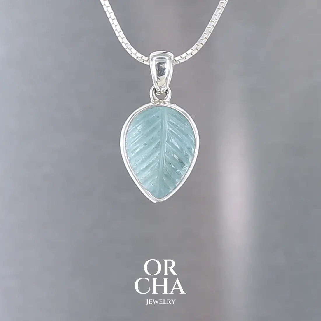 Pendentif pour femme en argent massif serti d'une topaze bleue sculptée en forme de feuille d'arbre. Pierre de couleur bleu ciel lumineux. Bijoux unique, éthique et durable présenté dans un coffret de notre marque, prêt à offrir. Livraison offerte, certificat d'authenticité, service client.