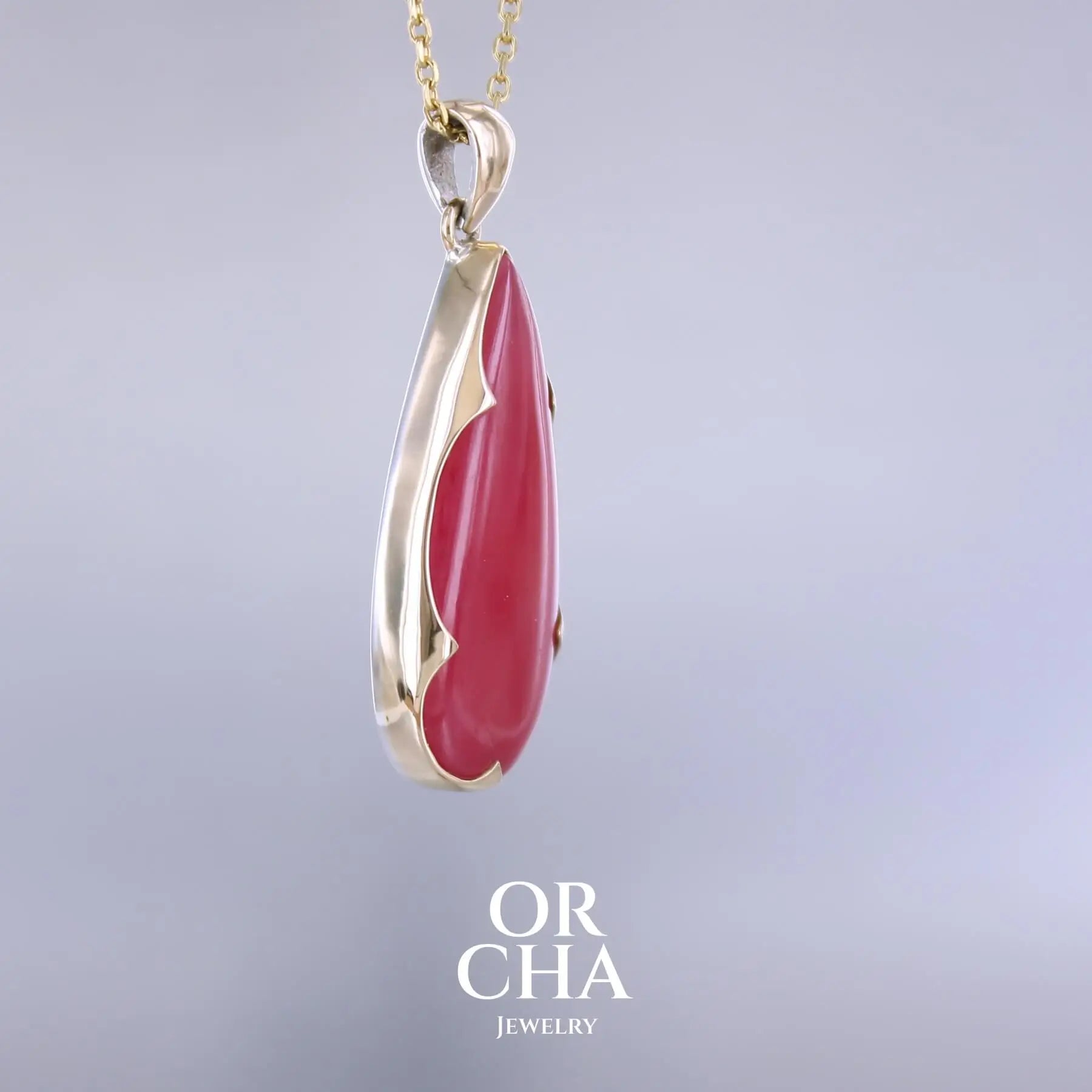 Pendentif pour femme en or jaune massif 18k et argent massif serti d'une Rhodonite rouge coquelicot de qualité rare. Pierre naturelle taillée en cabochon en forme de goutte de qualité translucide. Bijoux unique, éthique et durable présenté dans un coffret de notre marque, prêt à offrir. Livraison offerte, certificat d'authenticité, service client