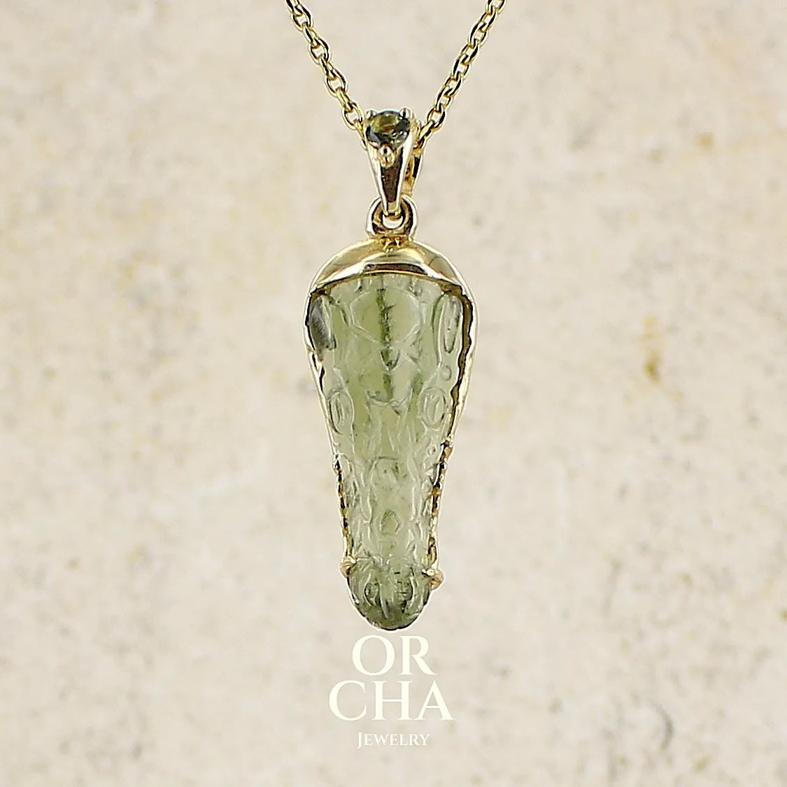 Pendentif pour homme en or 18k serti d'une moldavite sculptée en tête de crocodile. Pierre naturelle de couleur verte kaki translucide. Bijoux unique par Orcha jewelry