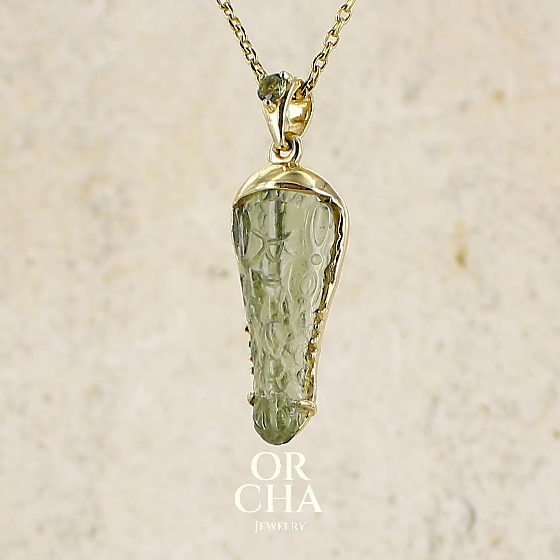 Pendentif pour homme en or 18k serti d'une moldavite sculptée en tête de crocodile. Pierre naturelle de couleur verte kaki translucide. Bijoux unique par Orcha jewelry