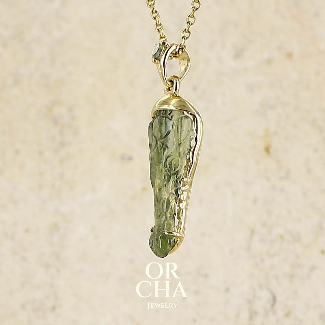 Pendentif pour homme en or 18k serti d'une moldavite sculptée en tête de crocodile. Pierre naturelle de couleur verte kaki translucide. Bijoux unique par Orcha jewelry