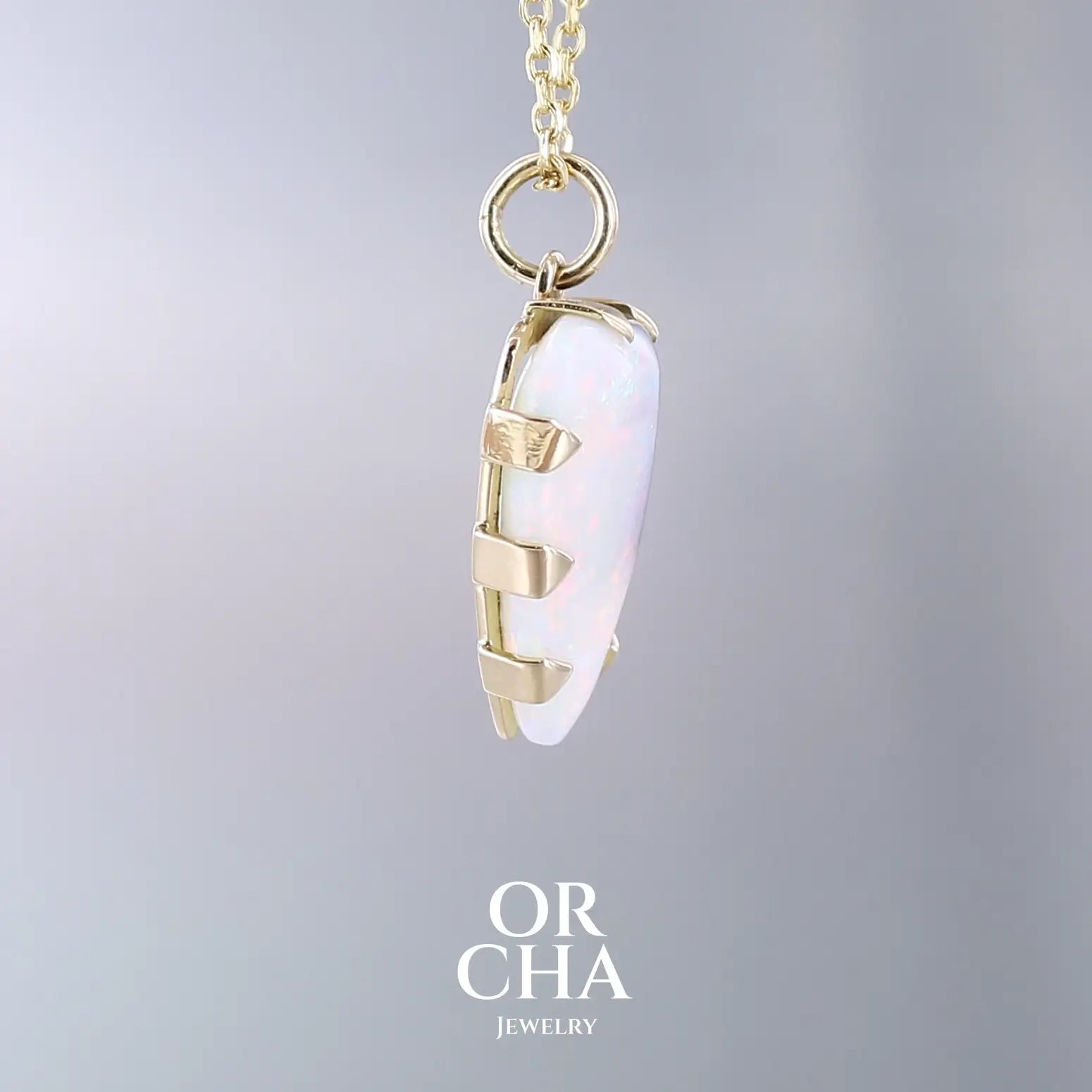 Pendentif pour femme en or jaune massif 18k serti d'une opale boulder aux feux multicolores. Majoritairement blanche une inclusion de matrice brune ressort en surface de la pierre, lui conférant un charme fou. Pierre naturelle taillée en cabochon de forme libre serti de griffe. Bijoux unique, éthique et durable présenté dans un coffret de notre marque, prêt à offrir. Livraison offerte, certificat d'authenticité, service client