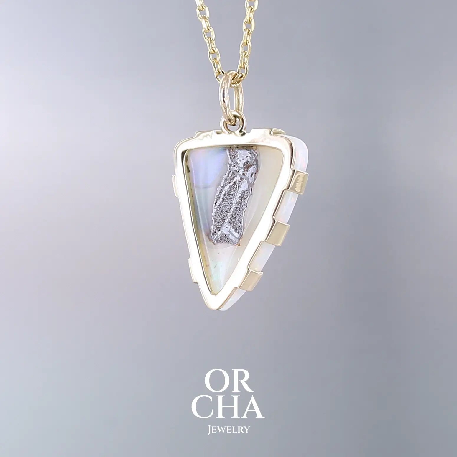 Pendentif pour femme en or jaune massif 18k serti d'une opale boulder aux feux multicolores. Majoritairement blanche une inclusion de matrice brune ressort en surface de la pierre, lui conférant un charme fou. Pierre naturelle taillée en cabochon de forme libre serti de griffe. Bijoux unique, éthique et durable présenté dans un coffret de notre marque, prêt à offrir. Livraison offerte, certificat d'authenticité, service client