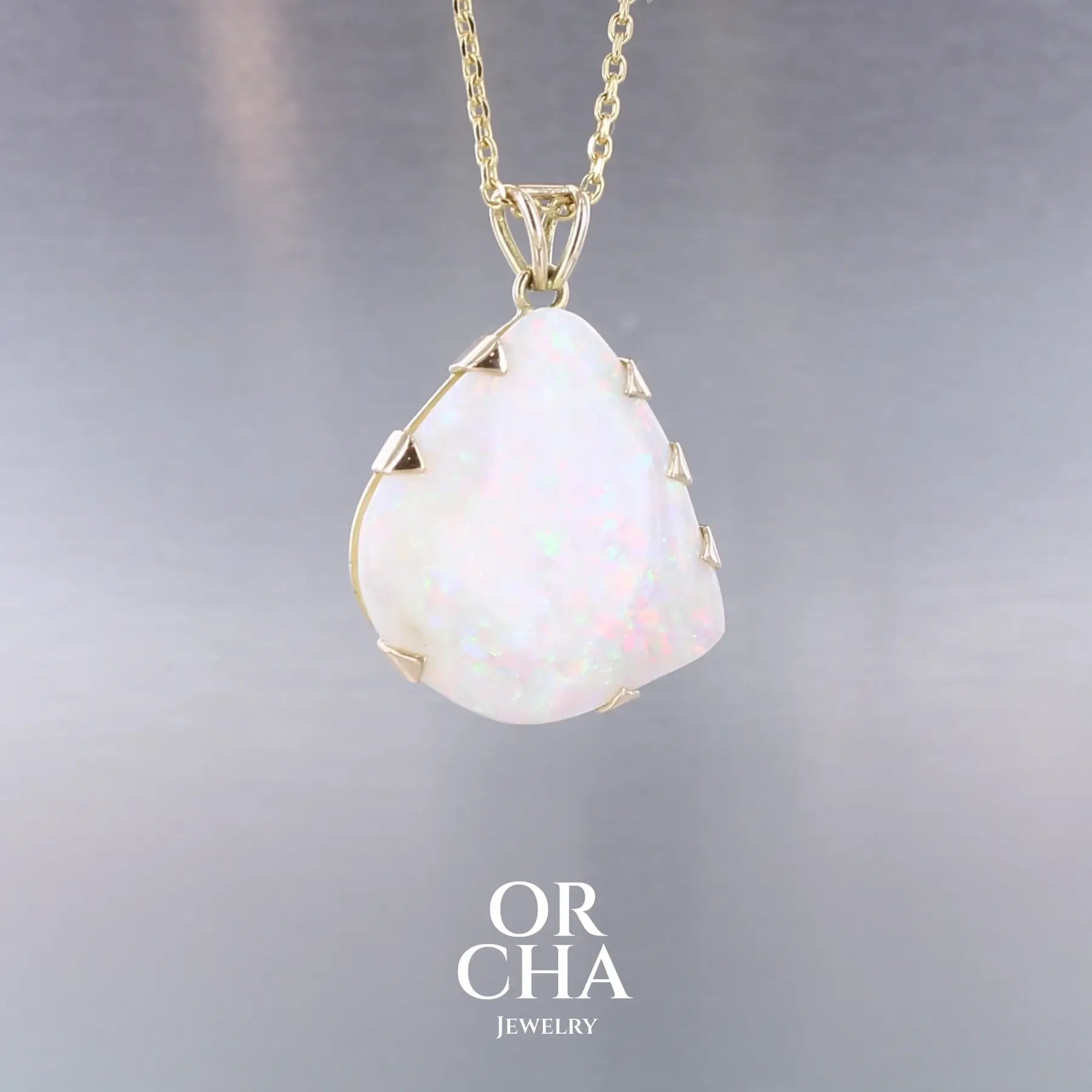 Pendentif pour femme en or jaune 18k serti d'une opale blanche de 17 carats aux feux multicolores. Pierre naturelle cabochon de forme irrégulière sertis de griffes. A noter: présence de roche mère de couleur crème au dos de la pierre. Bijoux unique, éthique et durable présenté dans un coffret de notre marque, prêt à offrir. Livraison offerte, certificat d'authenticité, service client