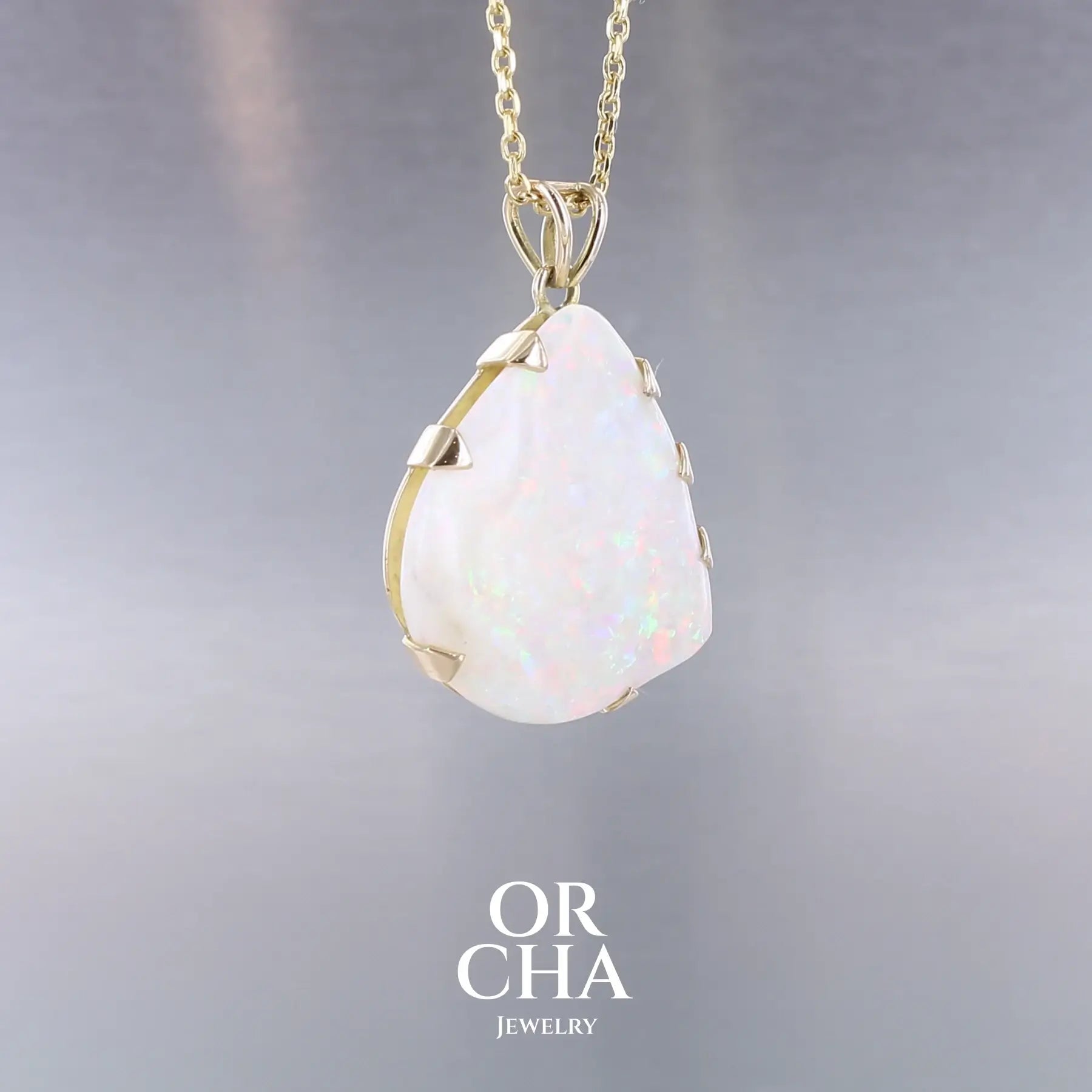 Pendentif pour femme en or jaune 18k serti d'une opale blanche de 17 carats aux feux multicolores. Pierre naturelle cabochon de forme irrégulière sertis de griffes. A noter: présence de roche mère de couleur crème au dos de la pierre. Bijoux unique, éthique et durable présenté dans un coffret de notre marque, prêt à offrir. Livraison offerte, certificat d'authenticité, service client