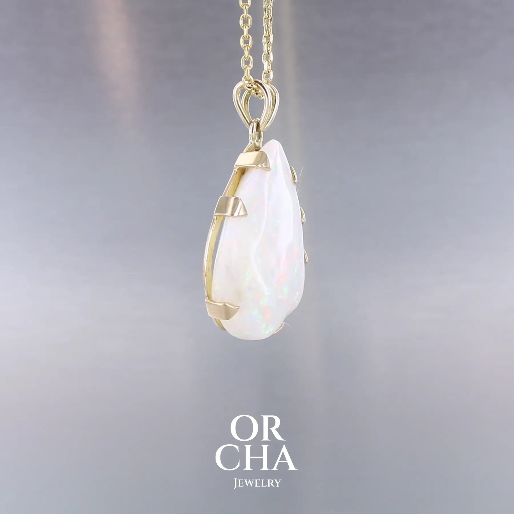 Pendentif pour femme en or jaune 18k serti d'une opale blanche de 17 carats aux feux multicolores. Pierre naturelle cabochon de forme irrégulière sertis de griffes. A noter: présence de roche mère de couleur crème au dos de la pierre. Bijoux unique, éthique et durable présenté dans un coffret de notre marque, prêt à offrir. Livraison offerte, certificat d'authenticité, service client