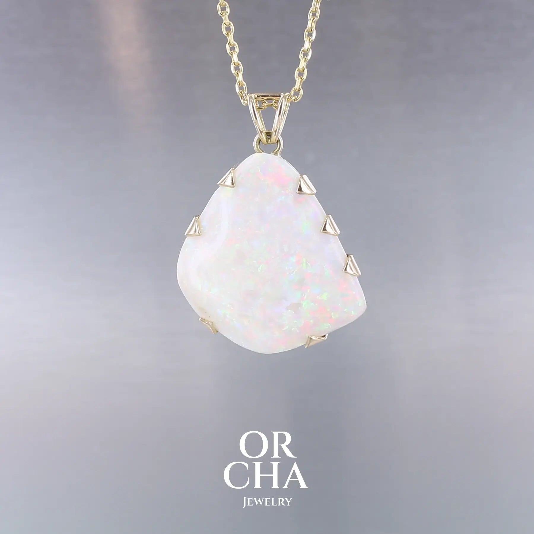 Pendentif pour femme en or jaune 18k serti d'une opale blanche de 17 carats aux feux multicolores. Pierre naturelle cabochon de forme irrégulière sertis de griffes. A noter: présence de roche mère de couleur crème au dos de la pierre. Bijoux unique, éthique et durable présenté dans un coffret de notre marque, prêt à offrir. Livraison offerte, certificat d'authenticité, service client