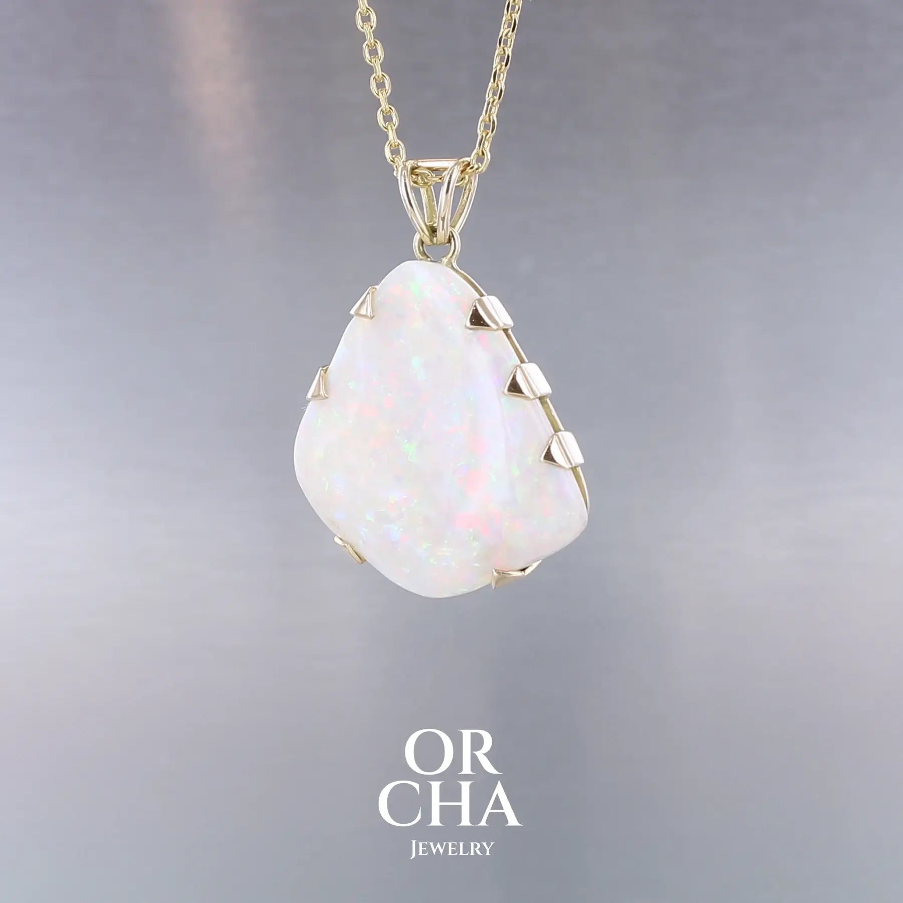 Pendentif pour femme en or jaune 18k serti d'une opale blanche de 17 carats aux feux multicolores. Pierre naturelle cabochon de forme irrégulière sertis de griffes. A noter: présence de roche mère de couleur crème au dos de la pierre. Bijoux unique, éthique et durable présenté dans un coffret de notre marque, prêt à offrir. Livraison offerte, certificat d'authenticité, service client