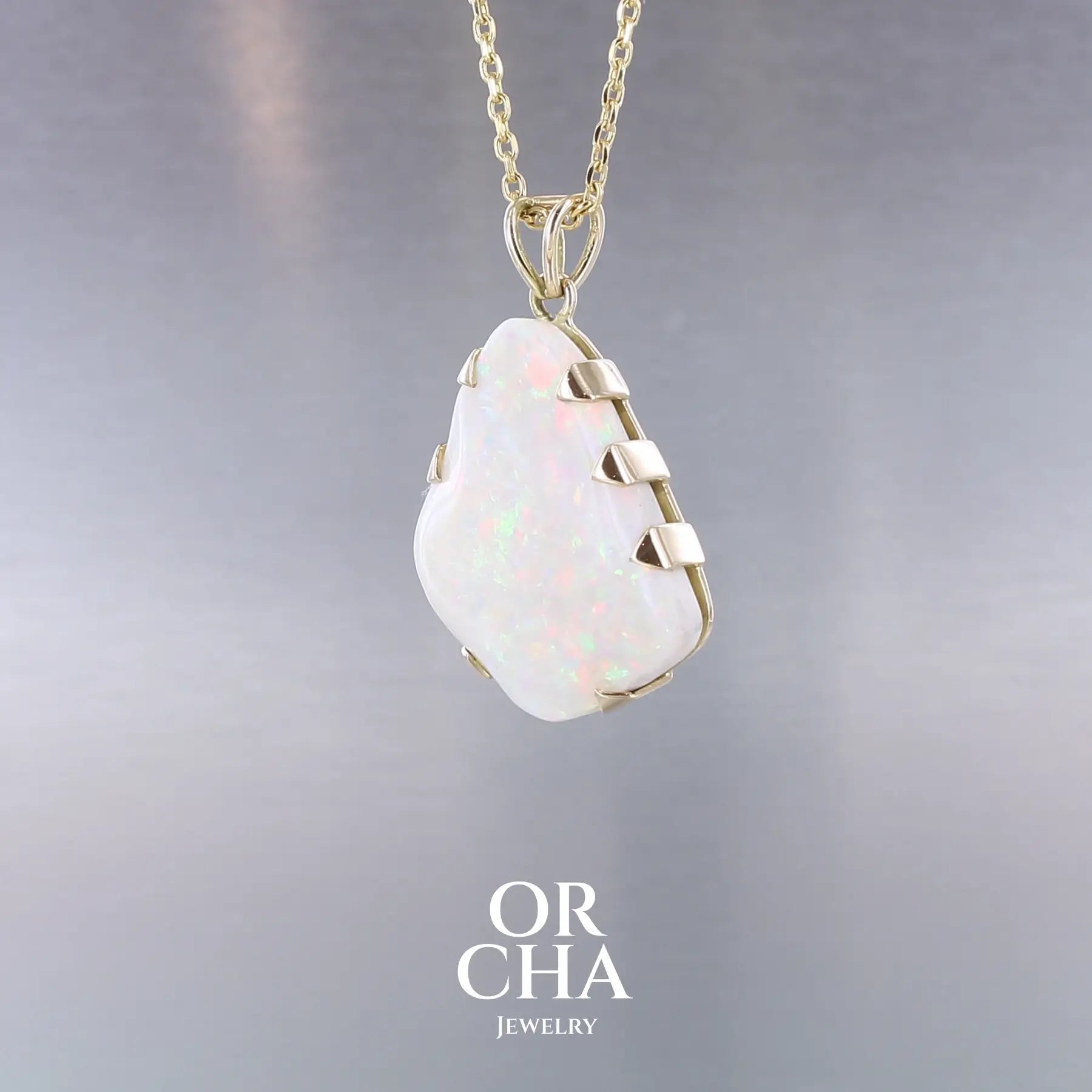Pendentif pour femme en or jaune 18k serti d'une opale blanche de 17 carats aux feux multicolores. Pierre naturelle cabochon de forme irrégulière sertis de griffes. A noter: présence de roche mère de couleur crème au dos de la pierre. Bijoux unique, éthique et durable présenté dans un coffret de notre marque, prêt à offrir. Livraison offerte, certificat d'authenticité, service client