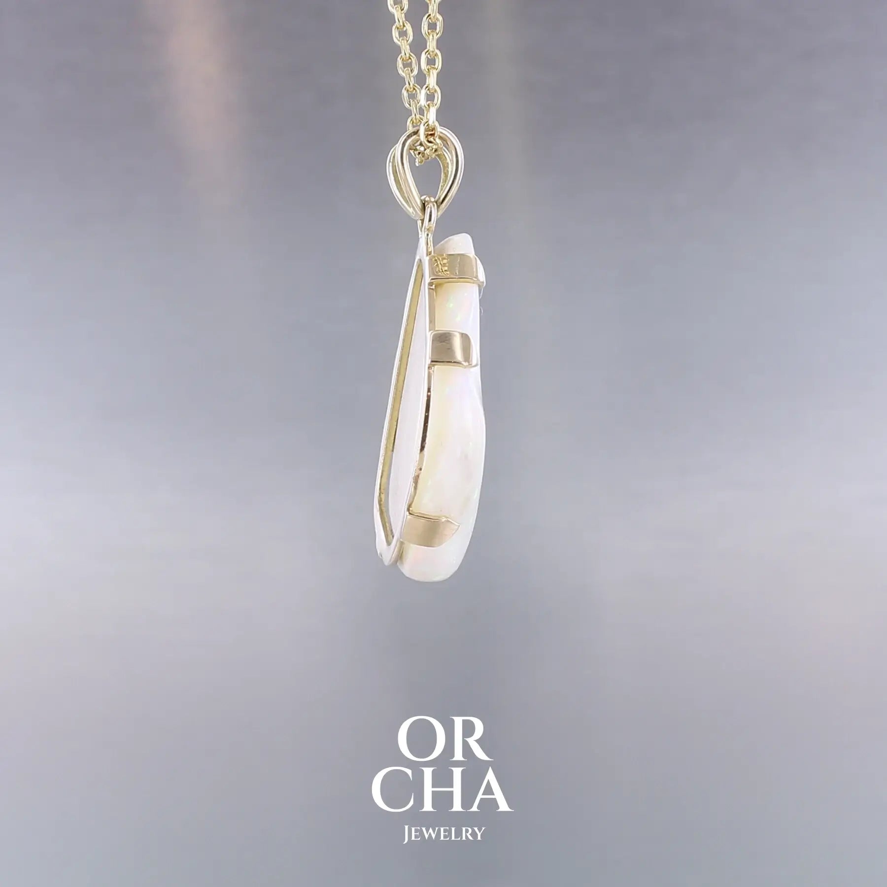 Pendentif pour femme en or jaune 18k serti d'une opale blanche de 17 carats aux feux multicolores. Pierre naturelle cabochon de forme irrégulière sertis de griffes. A noter: présence de roche mère de couleur crème au dos de la pierre. Bijoux unique, éthique et durable présenté dans un coffret de notre marque, prêt à offrir. Livraison offerte, certificat d'authenticité, service client