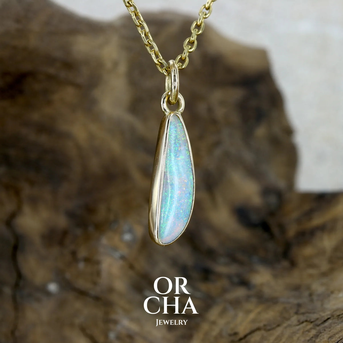 Pendentif pour femme en or jaune massif 18k serti d'une opale cristal aux feux étoilés multicolores à dominantes vert turquoises. Cabochon de 1 carat taille en forme de goutte de qualité transparente. Bijou unique réalisé par Orchajewelry