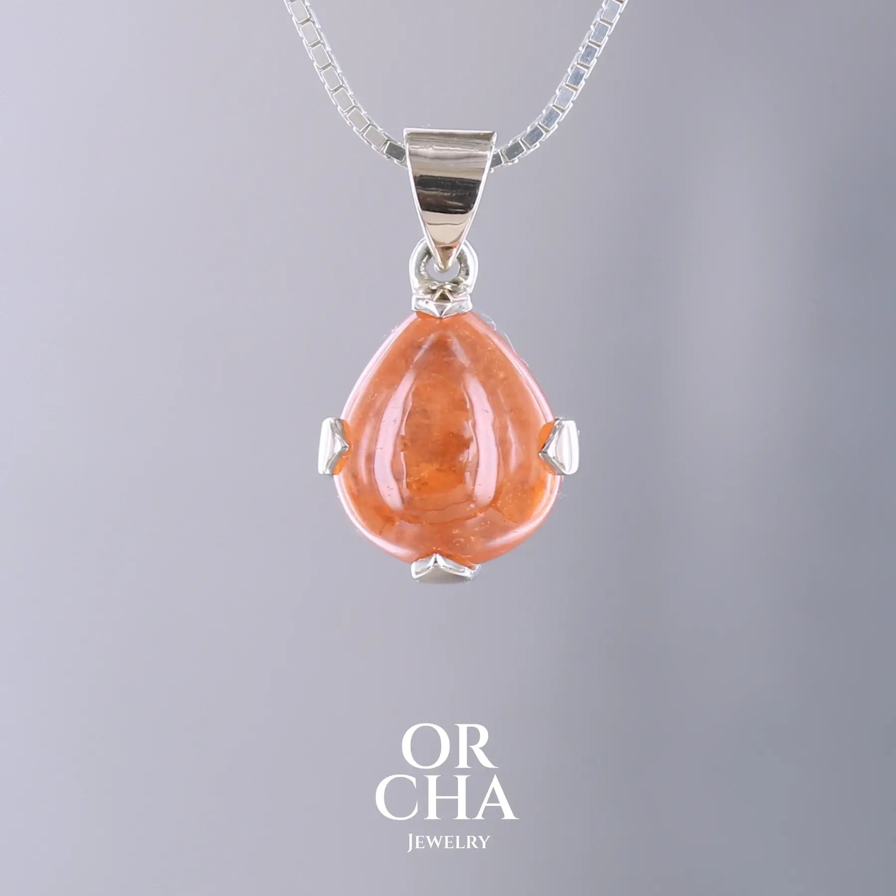 Pendentif en or jaune massif 9k et argent massif serti d'un grenat spessartite de 11,5 carats.  Cabochon en forme de goutte de couleur orange intense dit "Fanta color". Pierre transparente à inclusions. Bijoux unique, éthique et durable présenté dans un coffret de notre marque, prêt à offrir. Livraison offerte, certificat d'authenticité, service client.