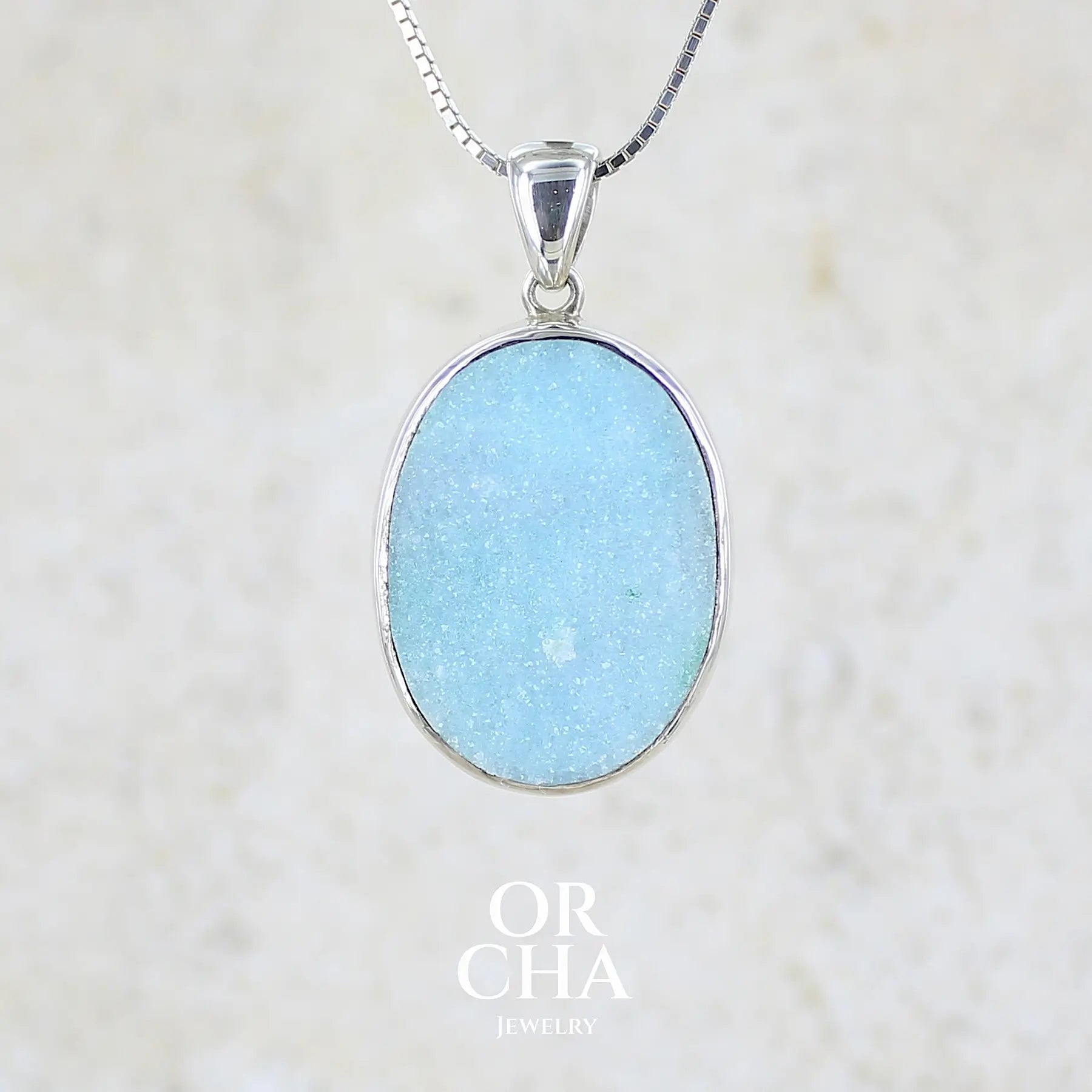 Pendentif pour femme en argent massif sertie d'un magnifique gemsilica druzy, chrysocolle silicifiée recouverte de fins cristaux de quartz scintillant. Pierre de qualité opaque taillée en tranche de forme ovale. Pierre naturelle originaire de République dominicaine du Congo de couleur bleu clair turquoise. pierre rare et unique