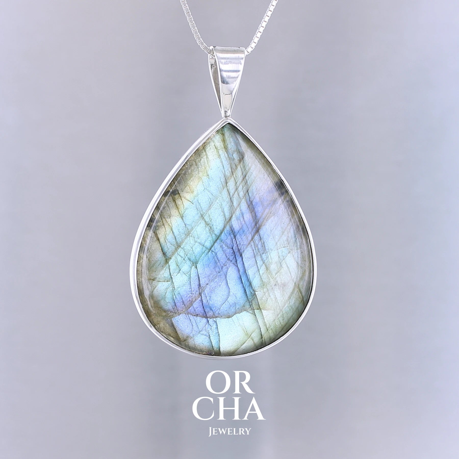 Pendentif pour femme en argent massif sertie d'une labradorite aux reflets bleus, bronzes et or selon la lumière. Pierre facettée naturelle translucide présentant des inclusions fréquents sur ce type de pierre. Bijoux unique, éthique et durable présenté dans un coffret de notre marque, prêt à offrir. Livraison offerte, certificat d'authenticité, service client.