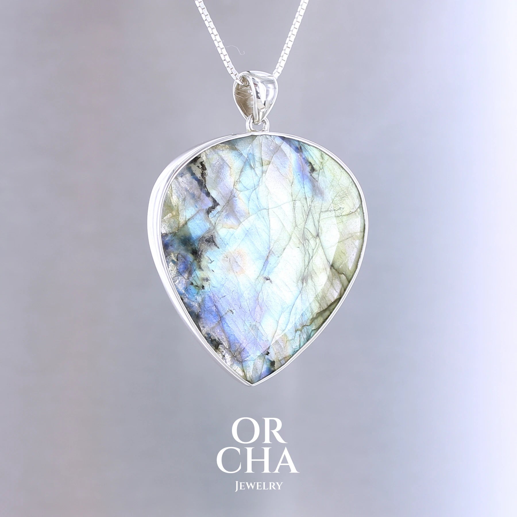 Pendentif pour femme en argent massif sertie d'une labradorite aux reflets bleus et bronze selon la lumière. Pierre facettée naturelle translucide présentant des inclusions fréquents sur ce type de pierre. Bijoux unique, éthique et durable présenté dans un coffret de notre marque, prêt à offrir. Livraison offerte, certificat d'authenticité, service client.