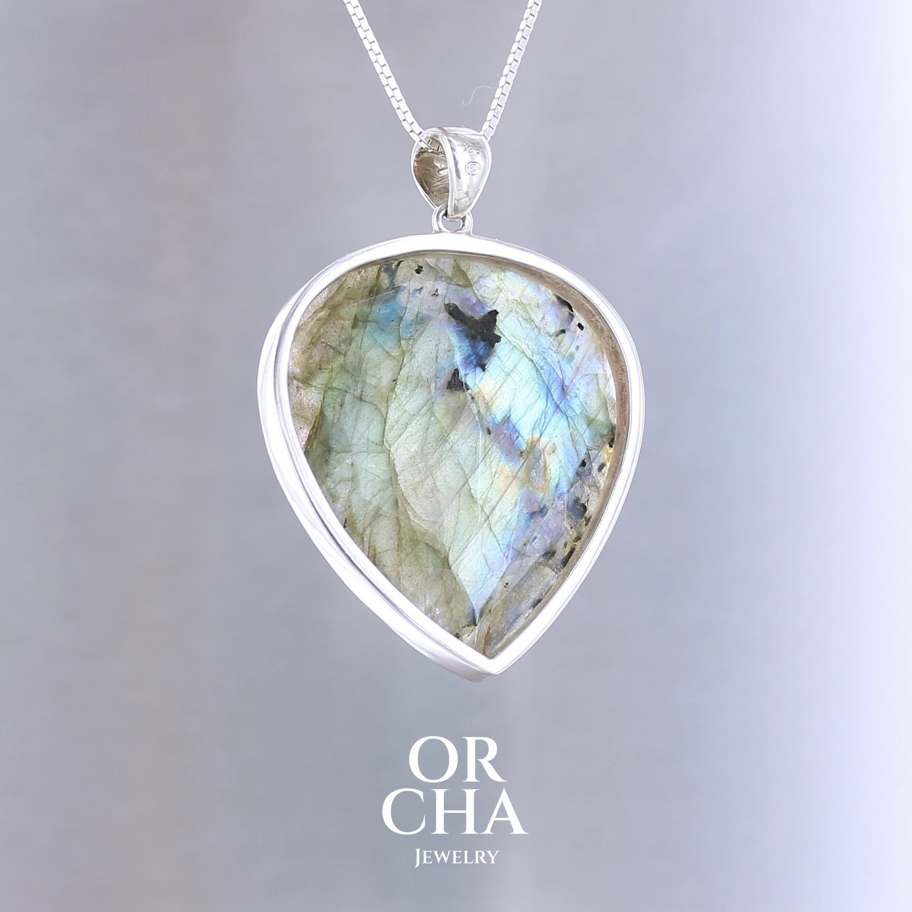 Pendentif pour femme en argent massif sertie d'une labradorite aux reflets bleus et bronze selon la lumière. Pierre facettée naturelle translucide présentant des inclusions fréquents sur ce type de pierre. Bijoux unique, éthique et durable présenté dans un coffret de notre marque, prêt à offrir. Livraison offerte, certificat d'authenticité, service client.