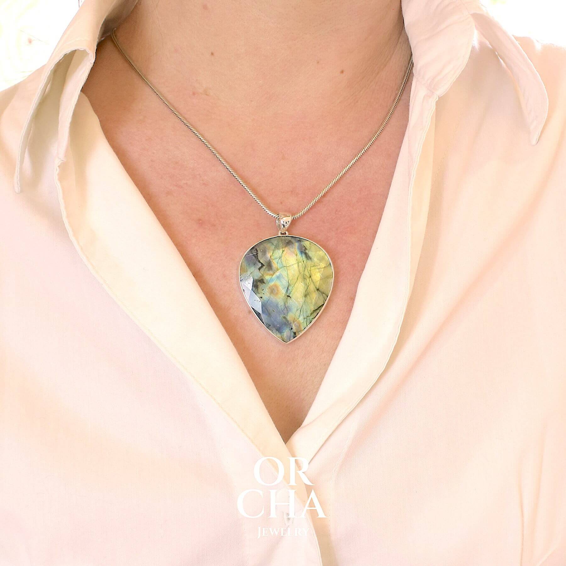 Pendentif porté pour femme en argent massif sertie d'une labradorite aux reflets bleus et bronze selon la lumière. Pierre facettée naturelle translucide présentant des inclusions fréquents sur ce type de pierre. Bijoux unique, éthique et durable présenté dans un coffret de notre marque, prêt à offrir. Livraison offerte, certificat d'authenticité, service client.