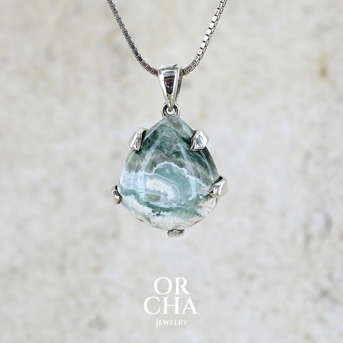 Pendentif pour femme en argent massif sertie d'un cabochon de jaspe océan de couleur nuancée de kaki et crème. Pierre opaque taillée en forme de goutte. Bijou unique par Orchajewelry