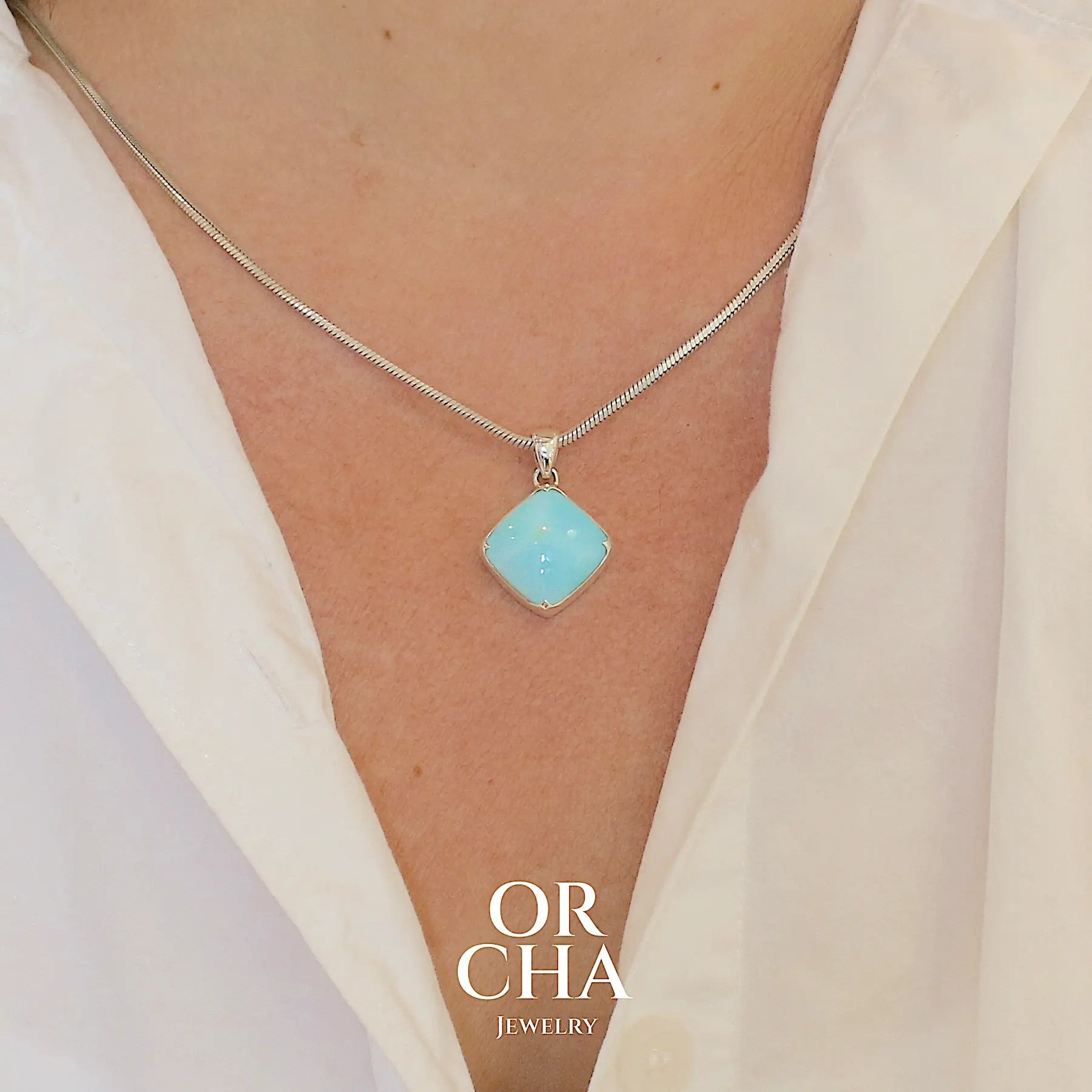 Pendentif en argent massif, sertie d'un cabochon d'opale bleue du Pérou de couleur bleu ciel clair. Pierre de forme carrée. Pierre opaque. Bijoux unique, éthique et durable présenté dans un coffret de notre marque, prêt à offrir. Livraison offerte, certificat d'authenticité, service client.