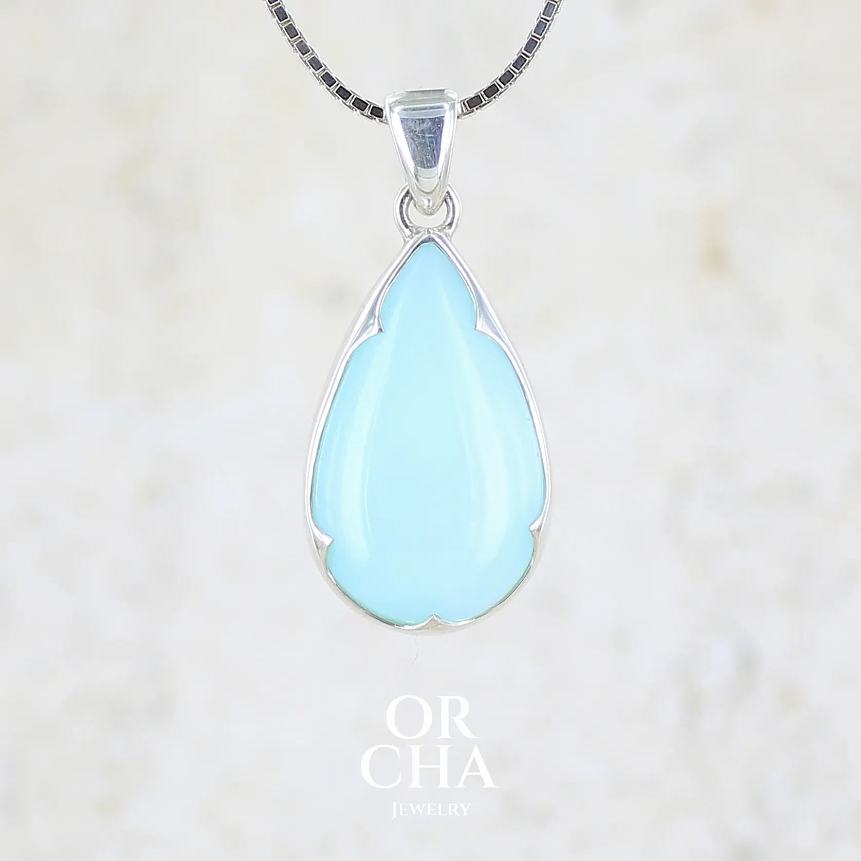 Pendentif pour femme en argent massif, sertie d'un cabochon d'opale bleue du Pérou de couleur bleu ciel clair. Pierre en forme de goutte. Pierre opaque. Bijoux unique, éthique et durable présenté dans un coffret de notre marque, prêt à offrir. Livraison offerte, certificat d'authenticité, service client.