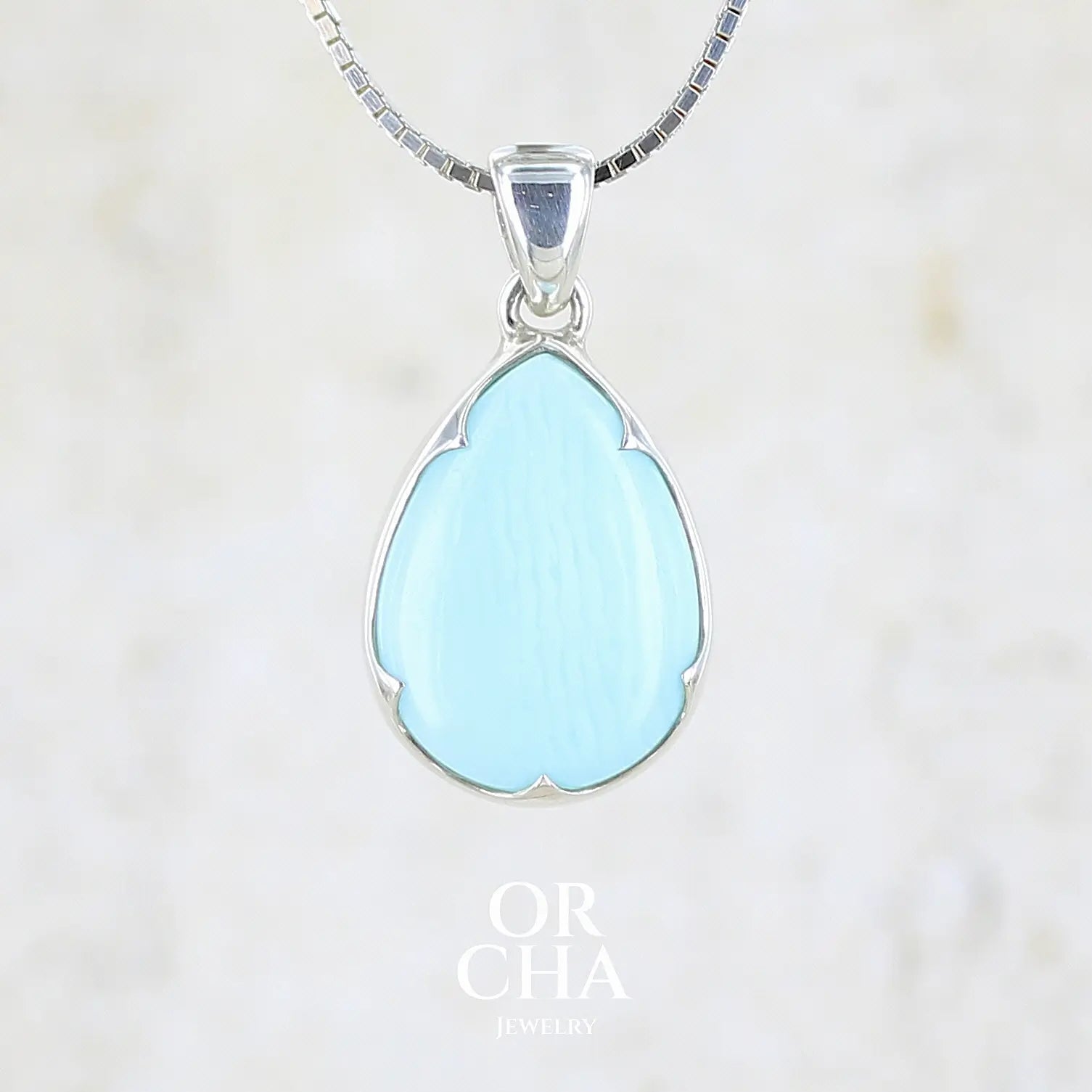 Pendentif pour femme en argent massif, sertie d'un cabochon d'opale bleue du Pérou de couleur bleu ciel clair. Pierre en forme de goutte. Pierre opaque. Bijoux unique, éthique et durable présenté dans un coffret de notre marque, prêt à offrir. Livraison offerte, certificat d'authenticité, service client.