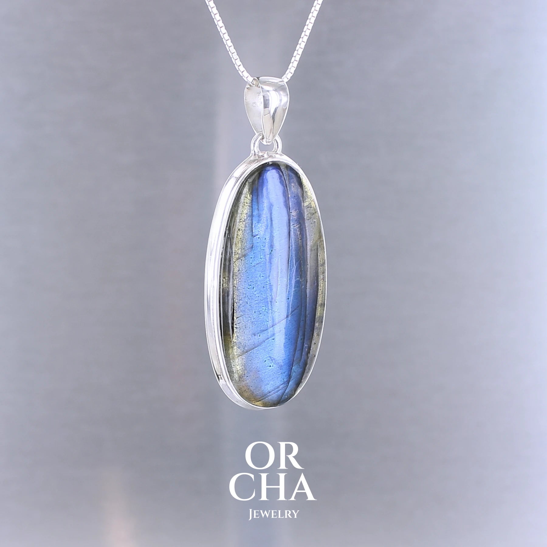 Pendentif pour femme en argent massif sertie d'une labradorite aux reflets bleus nuits selon la lumière. Pierre cabochon naturelle translucide présentant des inclusions fréquents sur ce type de pierre. Bijoux unique, éthique et durable présenté dans un coffret de notre marque, prêt à offrir. Livraison offerte, certificat d'authenticité, service client.