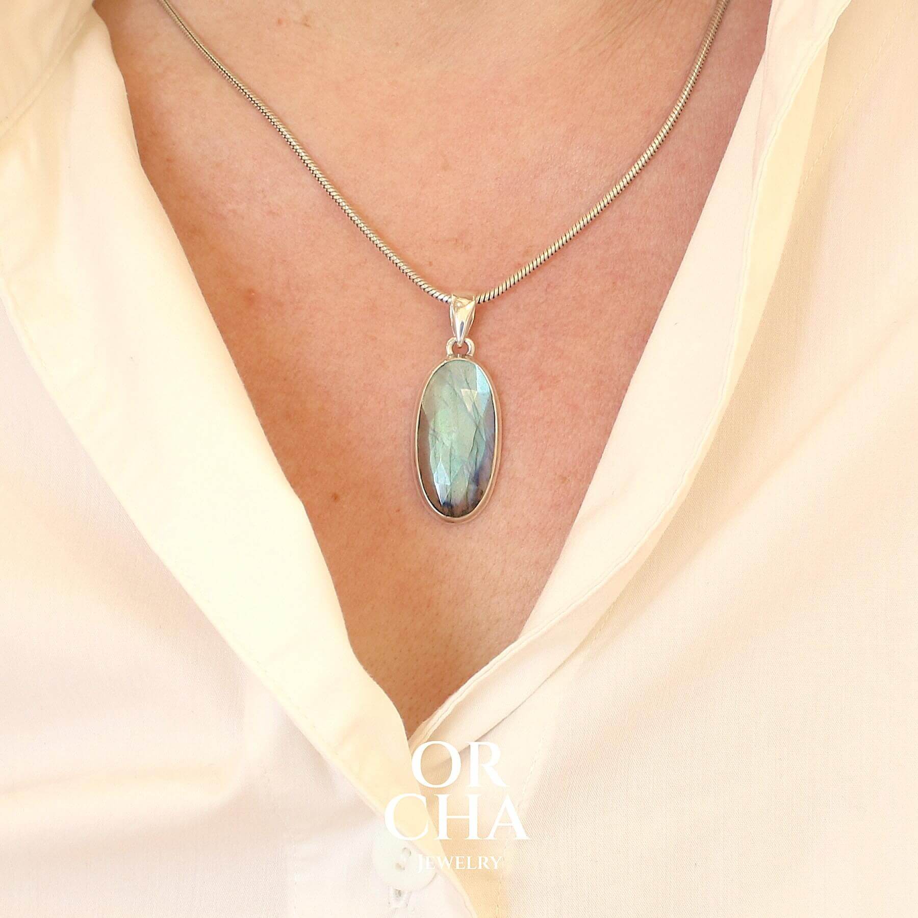 Pendentif pour femme en argent massif sertie d'une labradorite aux reflets bleus clairs selon la lumière. Pierre facettée naturelle translucide présentant des inclusions fréquents sur ce type de pierre. Bijoux unique, éthique et durable présenté dans un coffret de notre marque, prêt à offrir. Livraison offerte, certificat d'authenticité, service client.