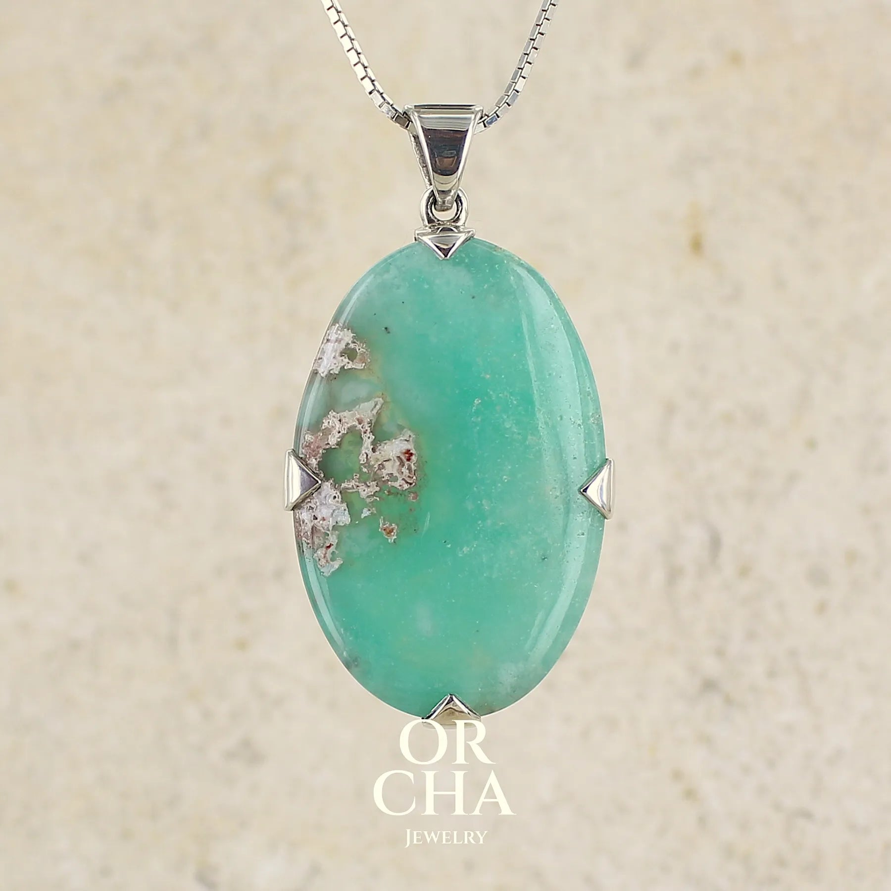 Pendentif ovale en argent massif, serti d'un cabochon de calcédoine de couleur bleue verte. Pierre de qualité translucide comportant des inclusions paysages blanches. Bijoux unique par Orcha Jewelry