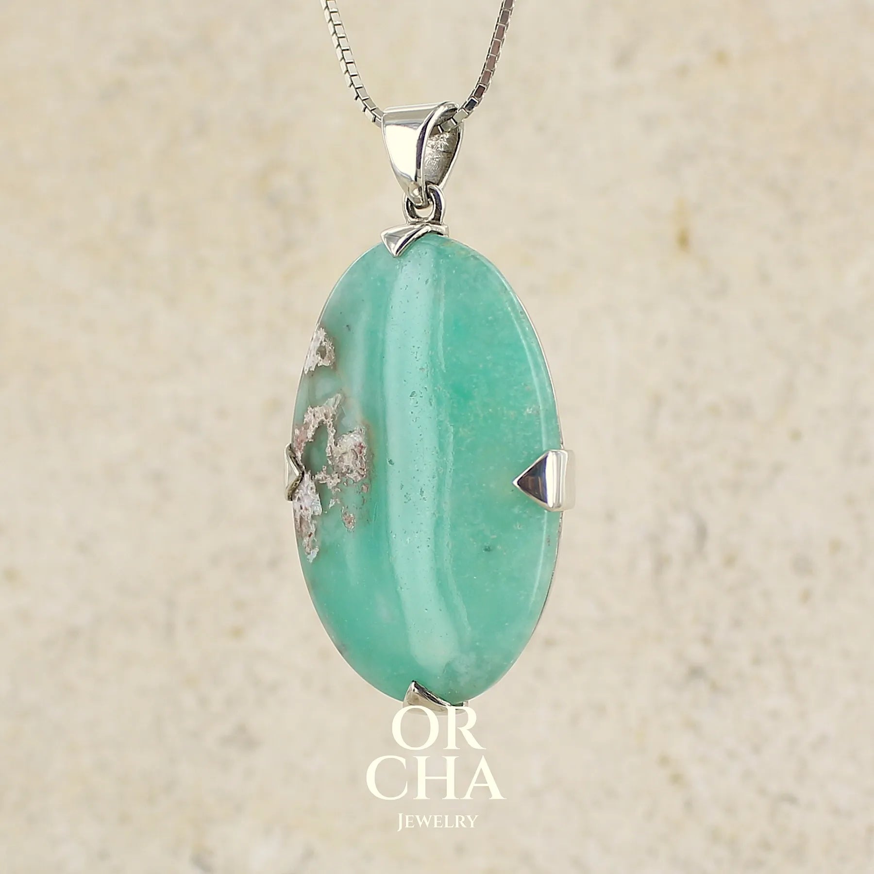 Pendentif ovale en argent massif, serti d'un cabochon de calcédoine de couleur bleue verte. Pierre de qualité translucide comportant des inclusions paysages blanches. Bijoux unique par Orcha Jewelry