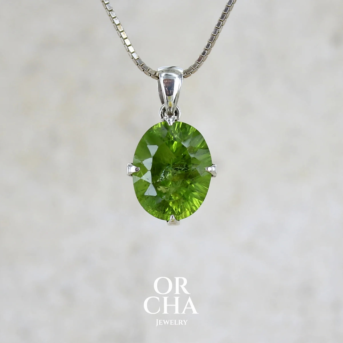 Pendentif pour femme en argent massif serti d'un péridot de couleur vert olive doré intense. Pierre taillée "laser cut", de forme ovale, transparente présentant de nombreuses inclusions. Bijou unique réalisé par Orchajewelry