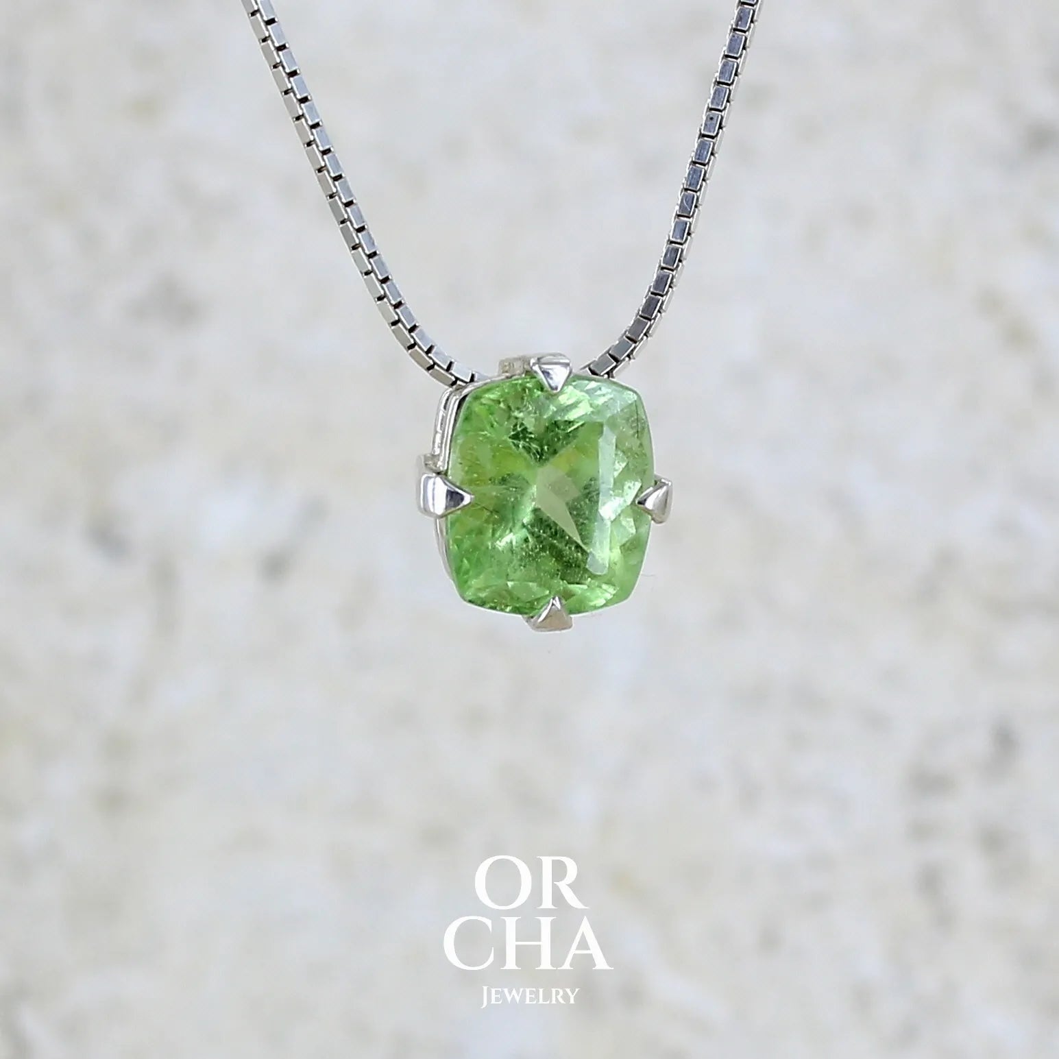 Collier solitaire pour femme en argent massif sertie d'un Péridot de couleur vert pastel anisé. Pierre facettée de forme carrée, qualité transparente présentant des inclusions. Pendentif monté sur une chaine en argent sterling de type maille miroir de 1,3 mm d'épaisseur et de 40cm de longueur. Bijoux unique réalisé par Orchajewelry