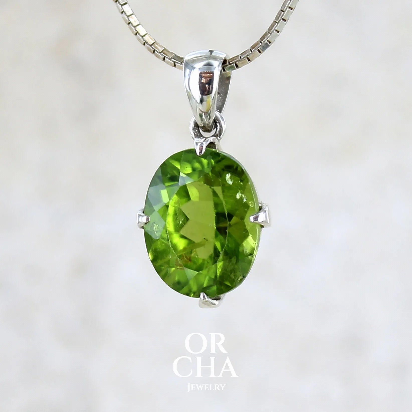 pendentif pour femme en argent massif serti d'un Péridot de couleur vert olive doré profond et intense . Pierre taillée transparente présentant des inclusions, de forme ovale. Bijoux unique par Orchajewelry