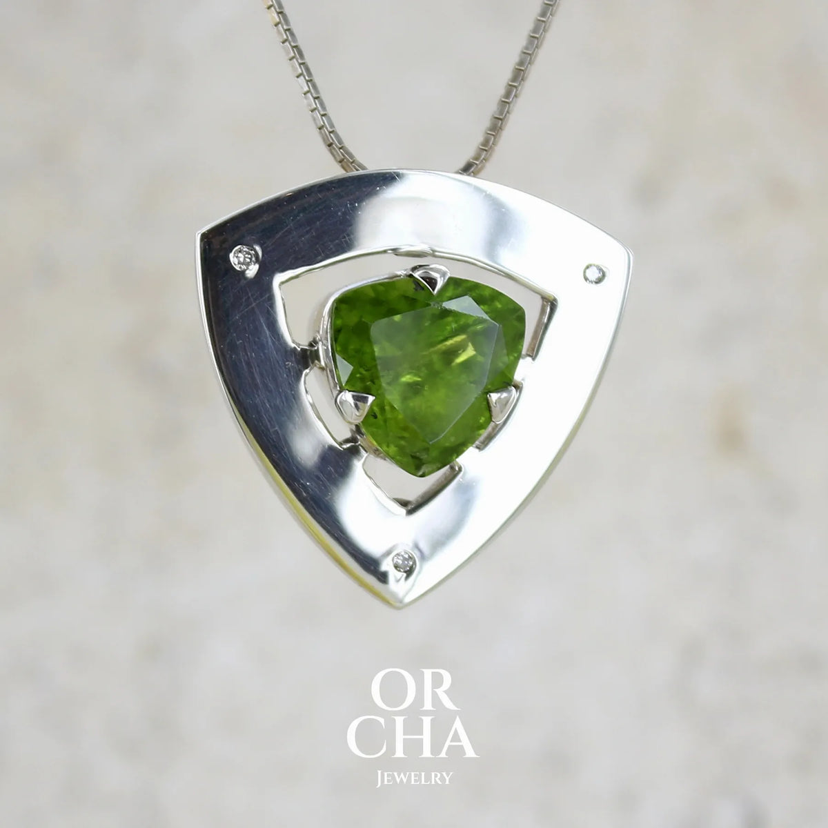 Pendentif contemporain pour femme en argent massif serti d'un péridot de couleur vert olive doré intense et de petits diamants. Pierre taillée, de forme triangulaire, transparente présentant de nombreuse inclusions. Bijou unique réalisé par Orchajewelry