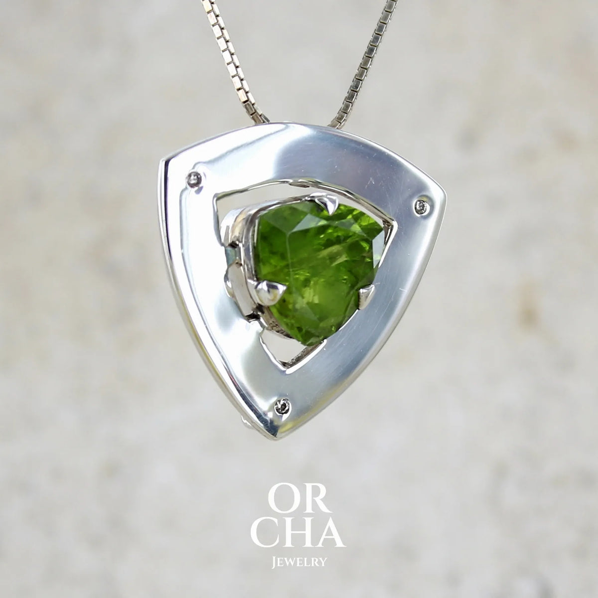 Pendentif contemporain pour femme en argent massif serti d'un péridot de couleur vert olive doré intense et de petits diamants. Pierre taillée, de forme triangulaire, transparente présentant de nombreuse inclusions. Bijou unique réalisé par Orchajewelry